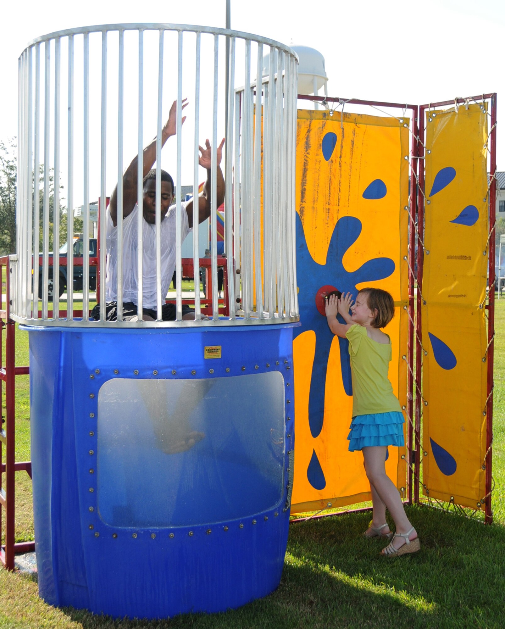 Master Sgt. Lee Utsey drops into the tank as Anna Coats, 7, tests the target on the dunking machine.  Anna’s parents are Tech. Sgt. Kristopher and Catherine Coats.  Sergeants Utsey and Coats are both assigned to the 335th TRS.  (U.S. Air Force photo by Kemberly Groue)
