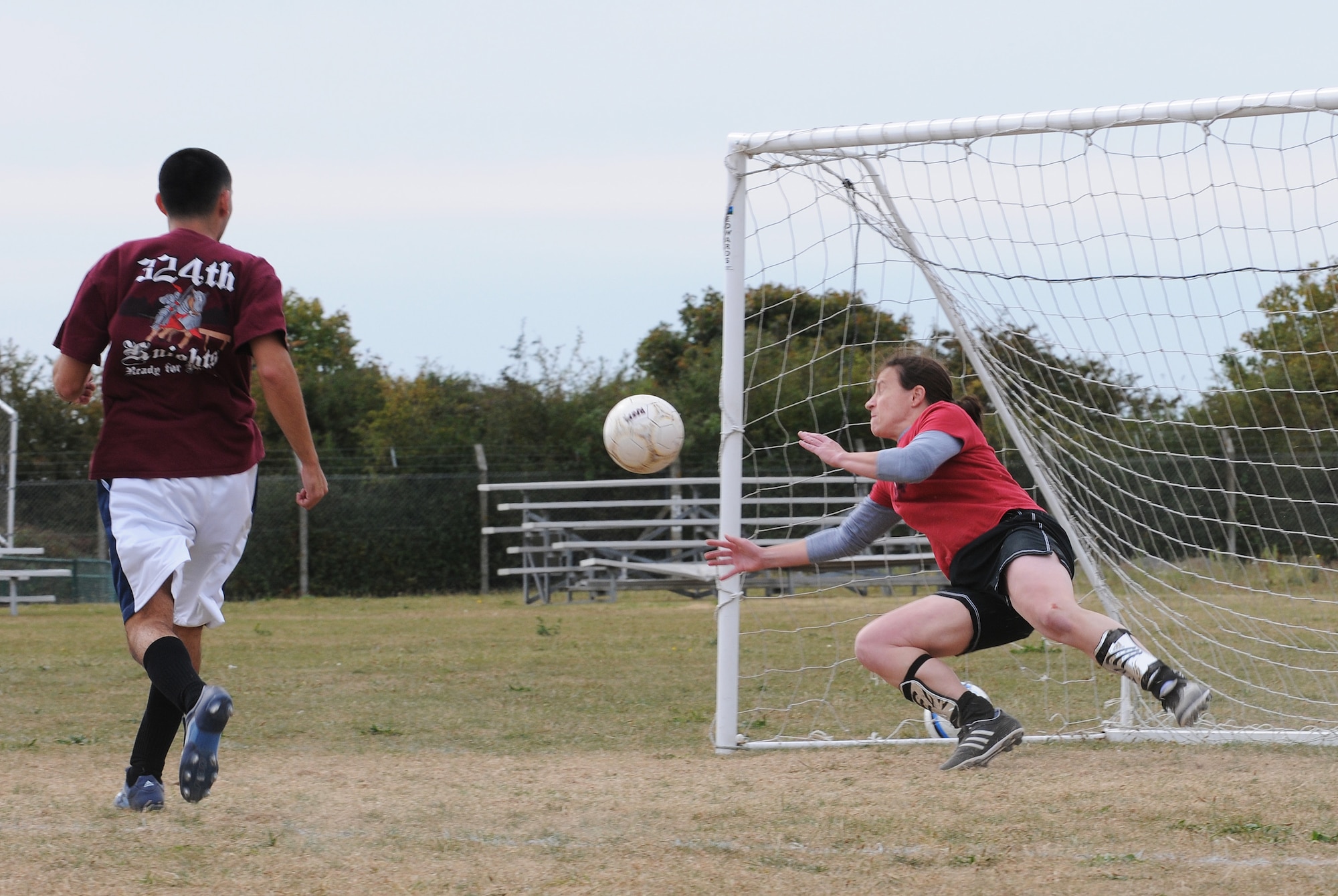 RAF MILDENHALL, England -- Goalkeeper Karen Wiekierak, 100th Operations Group player, dives to block a shot by an 100th Force Support Squadron player as it passes by defender Benito Carrasco, FSS, in intramural soccer play near the Hardstand Fitness Center here Sept. 21. The FSS put up a strong front with a full roster of seven players against OG's five player lineup. The lack of a full lineup contributed to OG's 1-4 loss. (U.S. Air Force photo/Senior Airman Thomas Trower)
