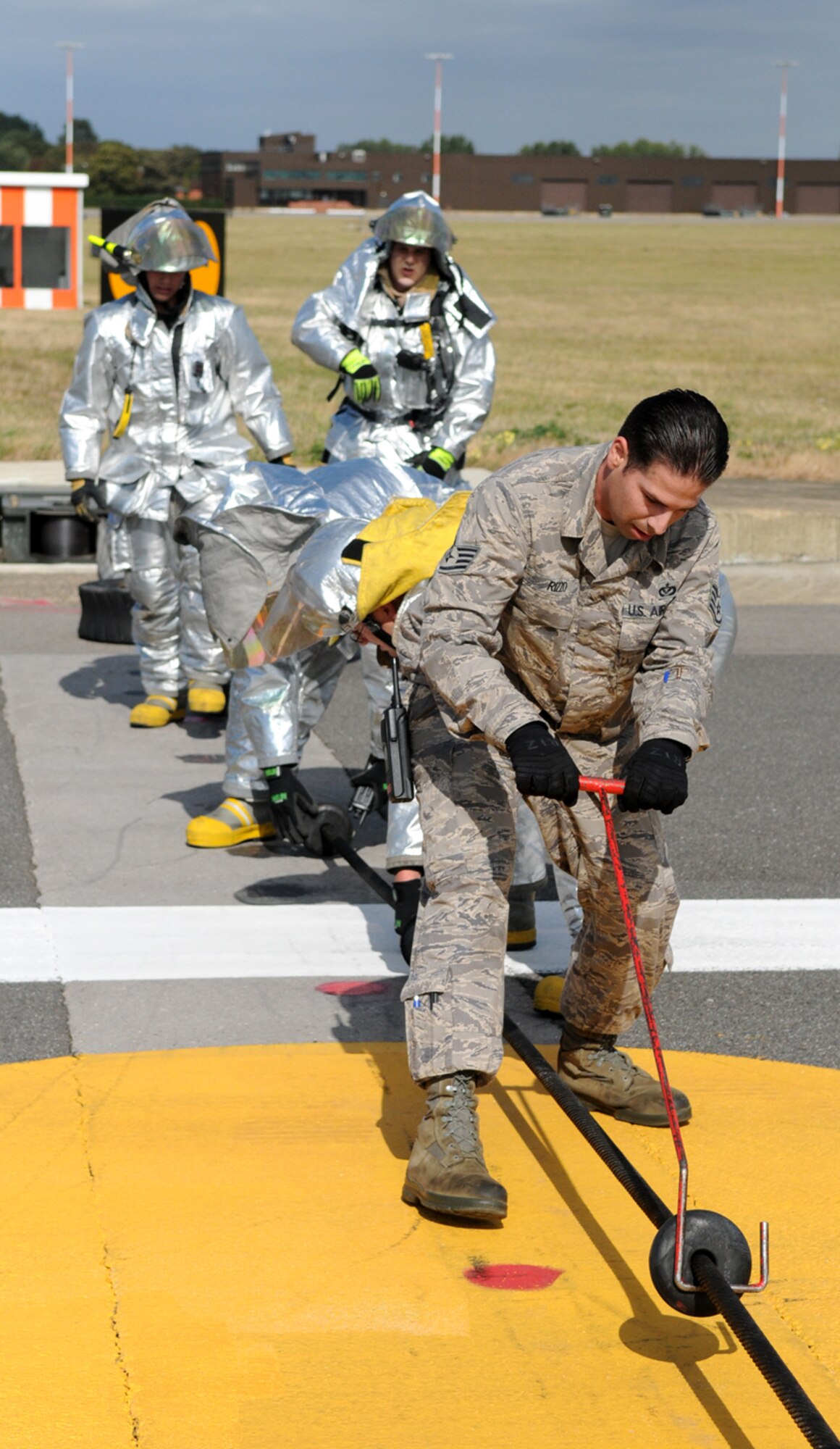 RAF MILDENHALL, England – Staff Sgt. Vincent Rizzo, 100th Civil Engineer Squadron barrier maintenance team, works with firefighters to reset the spacing between rubber “donuts” on one of two aircraft arresting cables here after an exercise Sept. 22.  The donuts hold the arresting cable two inches off the runway so it can be easily grabbed by an aircraft’s tailhook in an emergency.  The gear was engaged by an F-15 in a required annual test of the aircraft arresting system. (U.S. Air Force photo/Staff Sgt. Austin M. May)