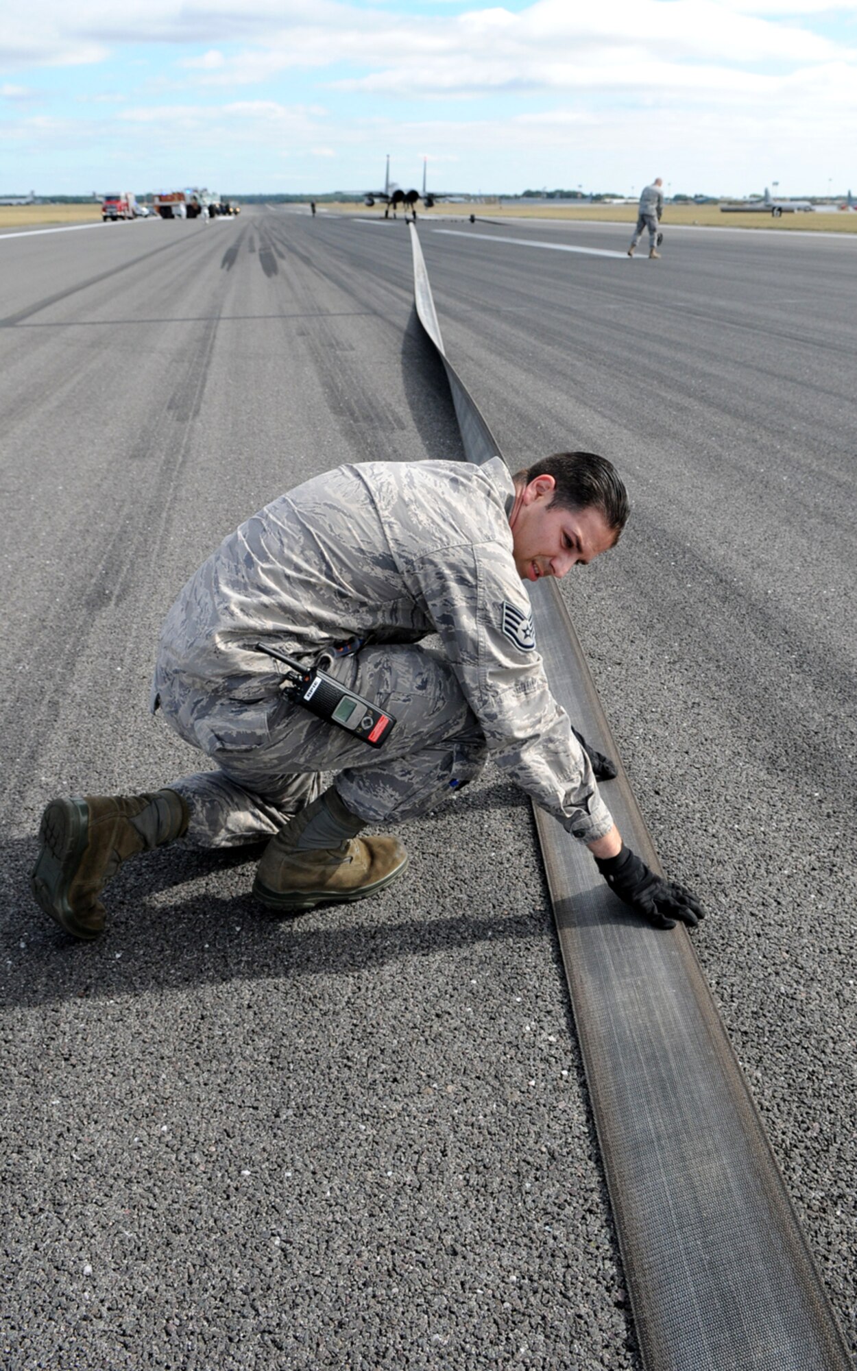 RAF MILDENHALL, England – Staff Sgt. Vincent Rizzo, 100th Civil Engineer Squadron barrier maintenance team, checks one of two 1,200-foot straps used to stop aircraft in an emergency on the RAF Mildenhall flight line.  The arresting gear must be checked after each use, and was used to stop an F-15 Sept. 22 during an annual maintenance test.  (U.S. Air Force photo/Staff Sgt. Austin M. May)