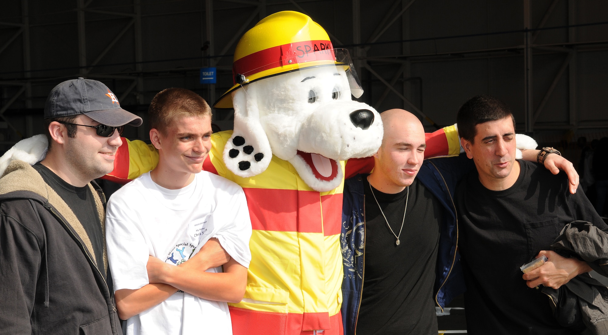 RAF MILDENHALL, England -- Chris Smith, a Joan Mann Special Sports Day participant (white shirt), and his escorts pose for a photo with Sparky, RAF Mildenhall Fire Department mascot, at Hangar 711 Sept. 19. Airmen from RAFs Mildenhall and Lakenheath volunteered to escort special-needs athletes through a variety of sporting events at the 28th annual sports day. (U.S. Air Force photo/Senior Airman Thomas Trower)