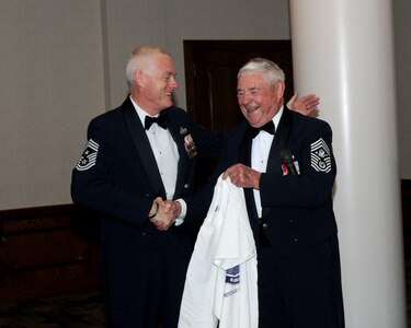 Retired Chief Master Sgt. of the Air Force Robert Gaylor (right), the 5th CMSAF, presents a T-shirt with his picture on it to Chief Master Sgt. Richard Kaiser, Air Force Personnel Center Command Chief, during the AFPC dining out Sept. 18.  The dining out was held to commemorate  the 62nd birthday of the Air Force.  (U.S. Air Force photo/Rich McFadden)