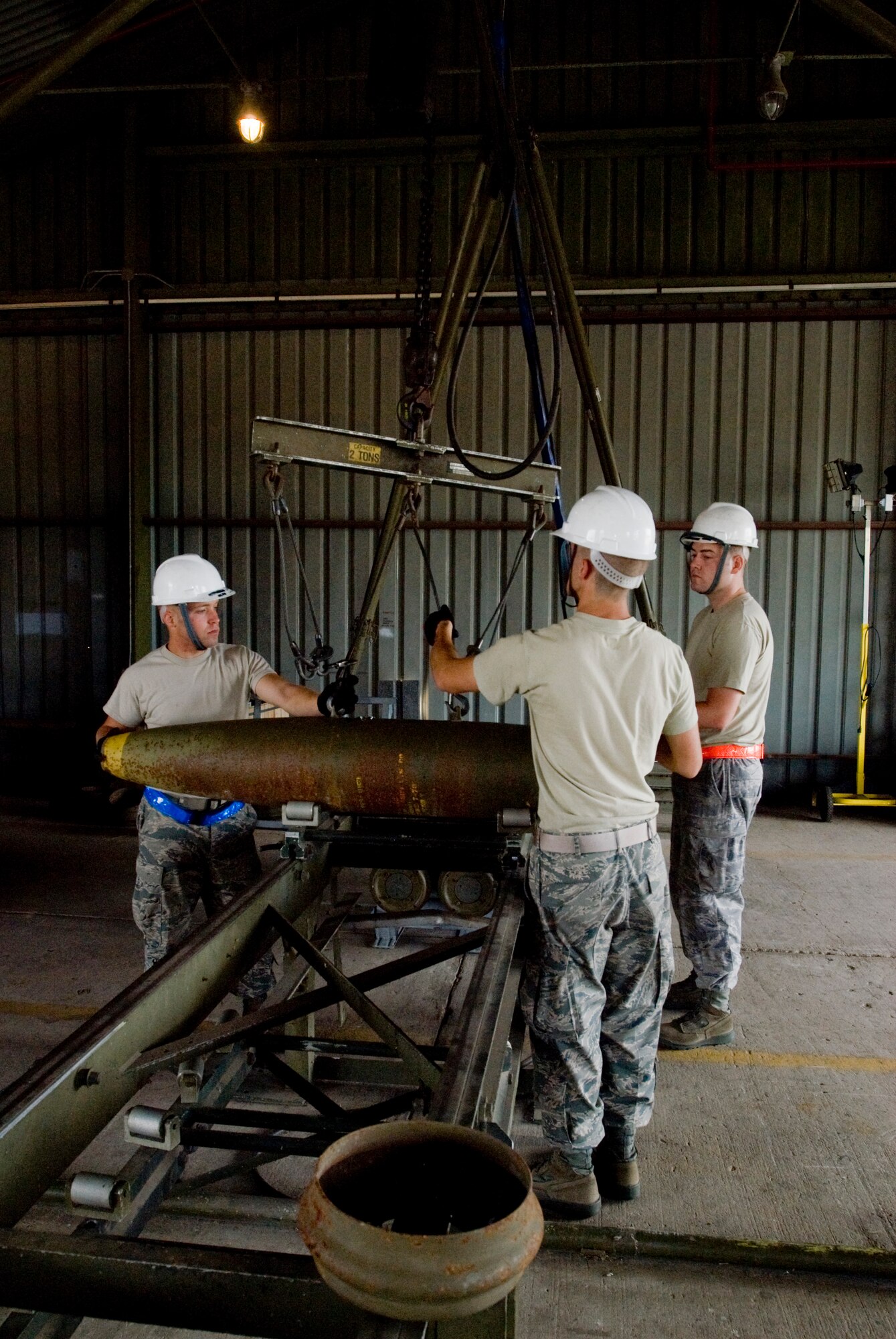 KUNSAN AIR BASE, Republic of Korea -- Airman 1st Class Robert Locke, Airman 1st Class Christopher Lewis and Senior Airman Michael Burdge, 8th Maintenance Squadron, prepare to hoist a MK-82, a 500 pound free fall, general- purpose bomb, to be put in storage Sept. 22. The MK-82 is being disassembled to preserve service life of the components for future use. (U.S. Air Force photo / Senior Airman Jonathan Steffen)