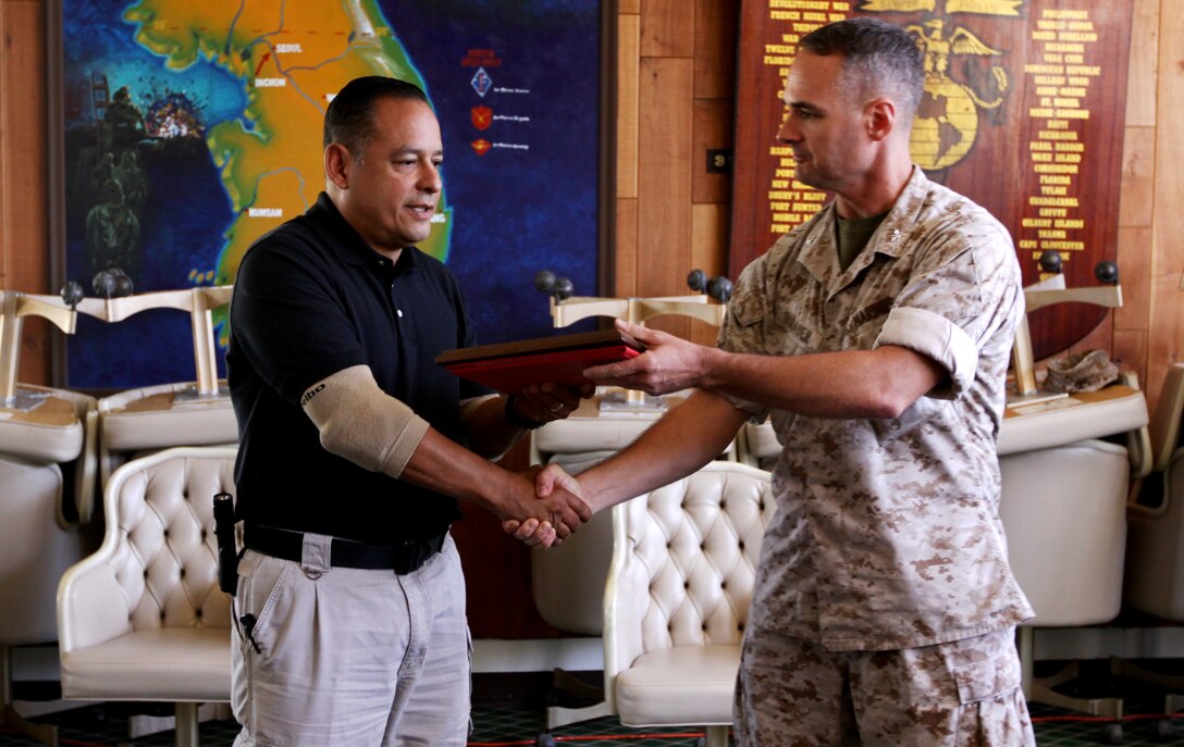 Col. Stephen R. Dinauer, commanding officer, Security Battalion, Camp Pendleton presents a superior achievement award to Jaime E. Rivadeneira, occupational safety and health specialist, Base Safety Office, Camp Pendleton for implementing a safety program which supported more than 7,000 Marines from Regimental Combat Team 1 in Iraq in 2008. The Superior Achievement Award for safety is given out by the commandant of the Marine Corps once a year to a civilian for outstanding safety accomplishments for the Marine Corps.