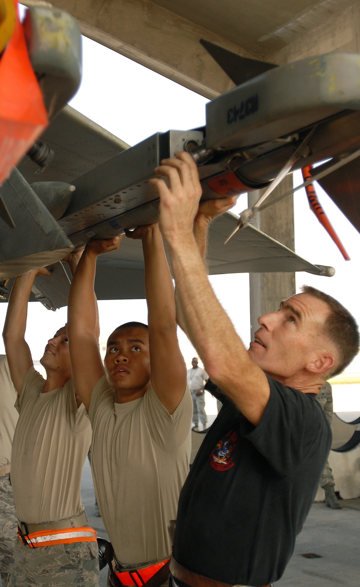 KADENA AIR BASE, Japan -- Airmen 1st Class Erik Schmidt and Thai Thatch, 67th Aircraft Maintenance Unit weapons loaders, help Senior Master Sgt. Robert Meyer, 67th AMU assistant superintendent, load an AIM-9 Sidewinder missile on an F-15 Eagle Sept. 18. After 28 years of service, Sergeant Meyer closed out his Air Force career with one final weapons load on an F-15 that was here when he was assigned at Kadena as an airman basic in 1982. The Laplace, Ill.-native, spent more than 17 years and wore every rank of his career while stationed at Kadena. (Air Force/Staff Sgt. Jason Lake)