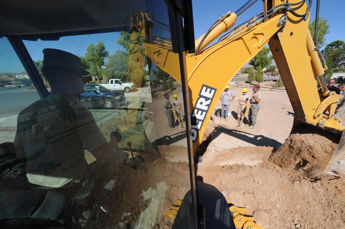 NELLIS AIR FORCE BASE, Nev. -- Tech. Sgt. Martin Spann, a 99th Civil Engineer Squadron pavements and construction operator, uses a backhoe to remove dirt from the surrounding area of a fire hydrant in the Nellis family campground, Sept. 23. The 99th Civil Engineers Squadron and is helping the utilities element replace 12 antiquated fire hydrants throughout the the campground.  (U.S. Air Force photo by Tech Sgt. Michael R. Holzworth)