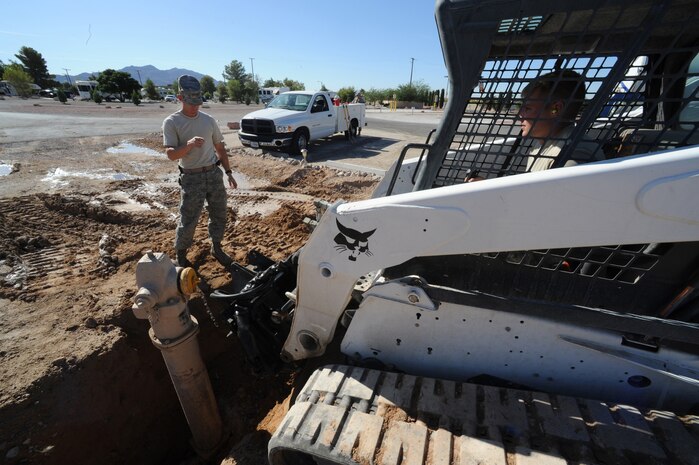 NELLIS AIR FORCE BASE, Nev. -- Tech. Sgt. Martin Spann directs Airman 1st Class Joseph Soper where to use a bobcat with a hydraulic jackhammer to break up a concrete "kicker" that keeps the main water line from bursting out the back of a fire hydrant in the  family campground, Sept. 23. Sergeant Spann and Airman Soper are 99th Civil Engineer Squadron pavements and construction operators helping replace 12 antiquated fire hydrants throughout the Nellis family campground.  
(U.S. Air Force photo by Tech Sgt. Michael R. Holzworth)
