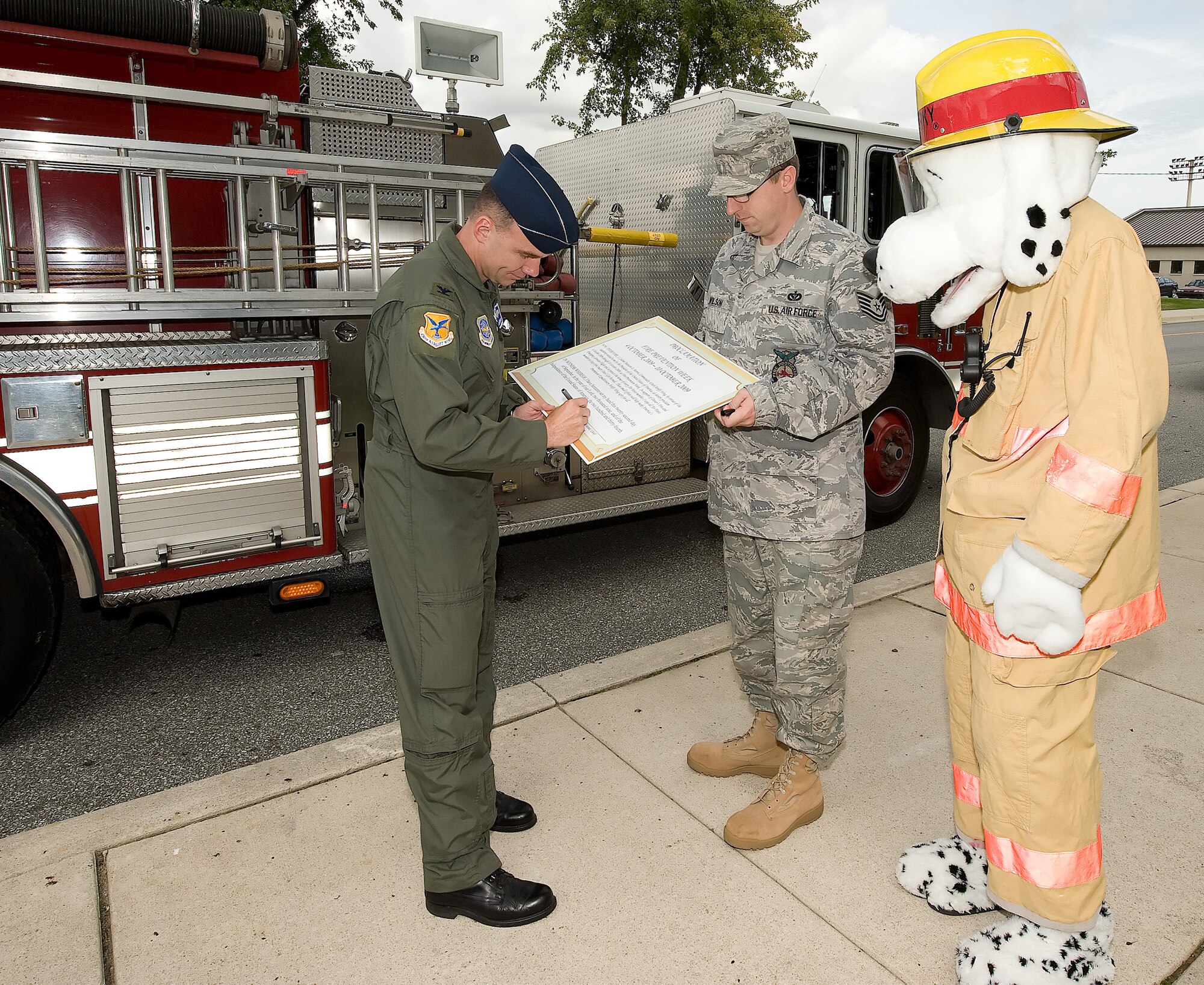 Col. Manson Morris, 436th Airlift Wing commander, signs a proclamation for Fire Prevention Week with Tech. Sgt. Donald Wilson, 436th Civil Engineer Squadron fire inspector, and Sparky the fire dog. Fire Prevention Week runs Oct. 4 through 10. (U.S. Air Force photo/Jason Minto) 