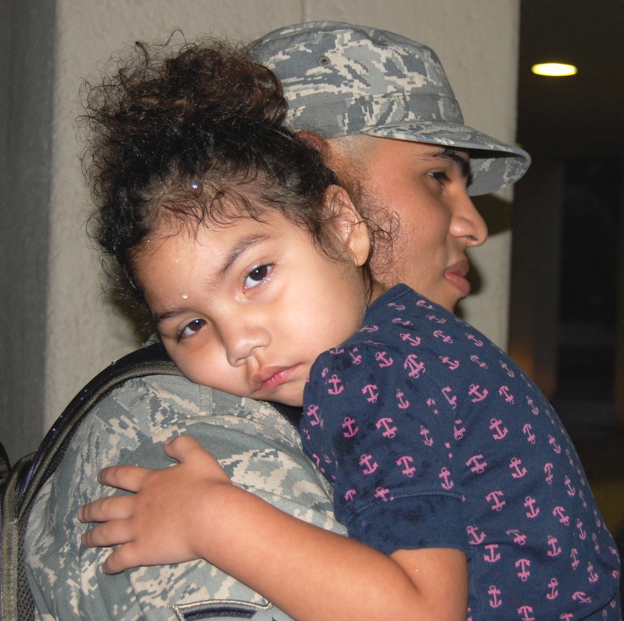 Senior Airman Alexandro Meza, 81st Medical Operations Squadron, holds daughter Daphne, 4, as he waits to board the bus taking him and nine other “Dragon Medics” to Louis Armstrong International Airport in New Orleans Sept. 12.  Families, friends and 81st Medical Group leaders gathered in front of Keesler Medical Center’s “A” tower to see the group off.  They deployed to Manas Air Base, Kyrgyzstan, for four months to serve as third-country national escorts.  More than 20 medics deployed over three days:  Sept. 12, 16 and Monday.  (U.S. Air Force photo by Steve Pivnick)