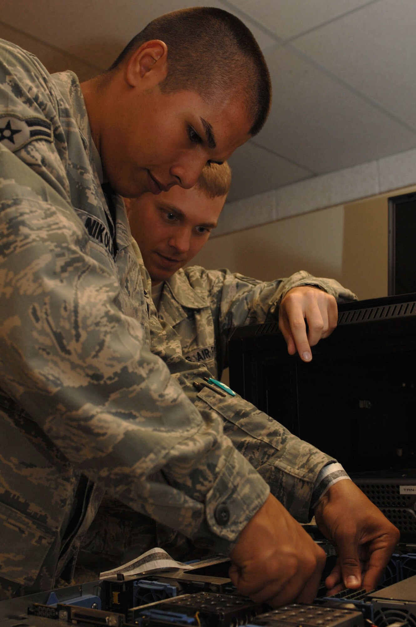 Staff Sgt. David Walker observes Airman 1st Class Mark Nikolas replacing a server memory card in the Network Control Center on Seymour Johnson Air Force Base, N.C., Sept. 16, 2009. Airmen working in the NCC are responsible for maintaining all data storage and e-mail servers and patching all systems. Sergeant Walker and Airman Nikolas are 4th Communications Squadron network operations technicians (U.S. Air Force photo by Staff Sgt. Heather Stanton)
