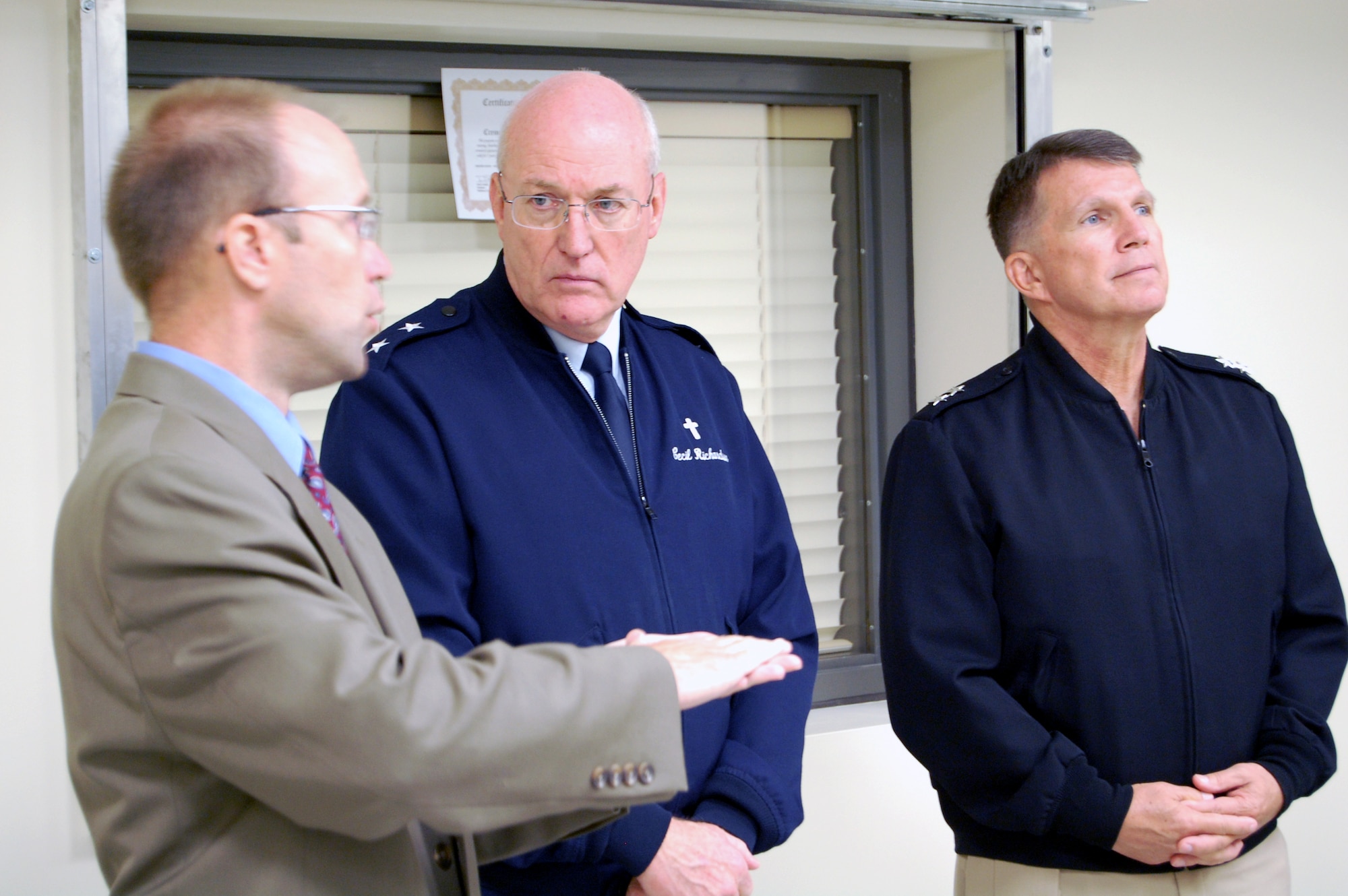 Mr. Trevor Dean, Deputy Commander, Air Force Mortuary Affairs Operation Center briefs Chaplain (Maj. Gen.) Cecil Richardson, U.S. Air Force,  and Chaplain (Rear Adm.) Robert Burt, U.S. Navy about current missions at AFMAO  U.S. Air Force photo by 1st Lt. Joseph Winter (Released)