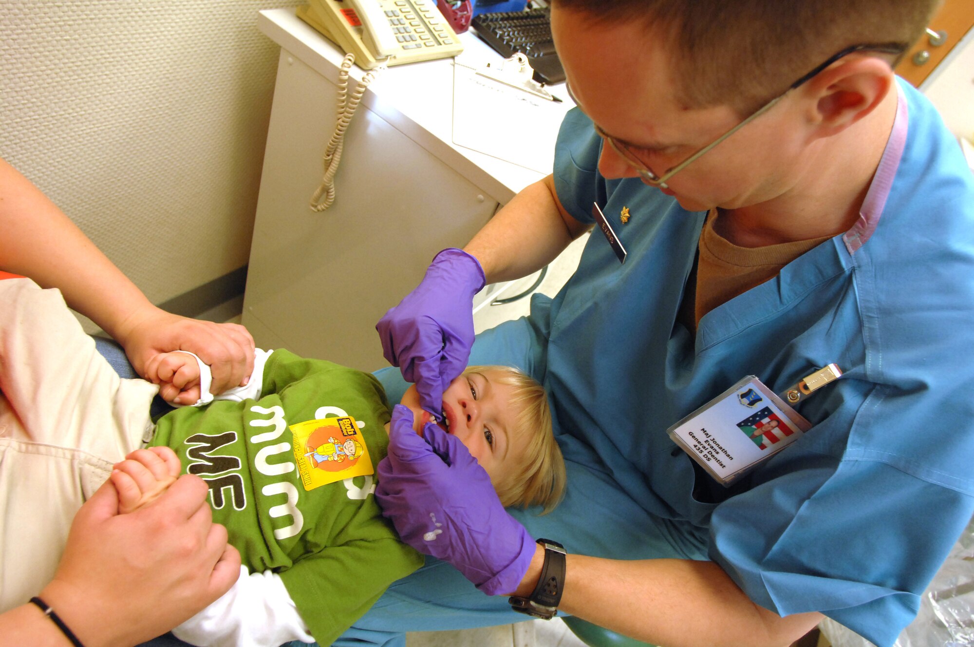 U. S. Air Force Maj. (Dr,) Jonathan Evan, 86th Medical Group general dentist, flosses Hayden Voss's teeth during his first trip to the dentist. Dentists at the 86th Dental Squadron see hundreds of children each year from the Kaiserslautern Military Community. For the initial visit, Doctor Evans emphasizes the importance of parental involvement and the child's overall dental well-being. (U.S. Air Force photo by Tech. Sgt. Michael Voss) 
