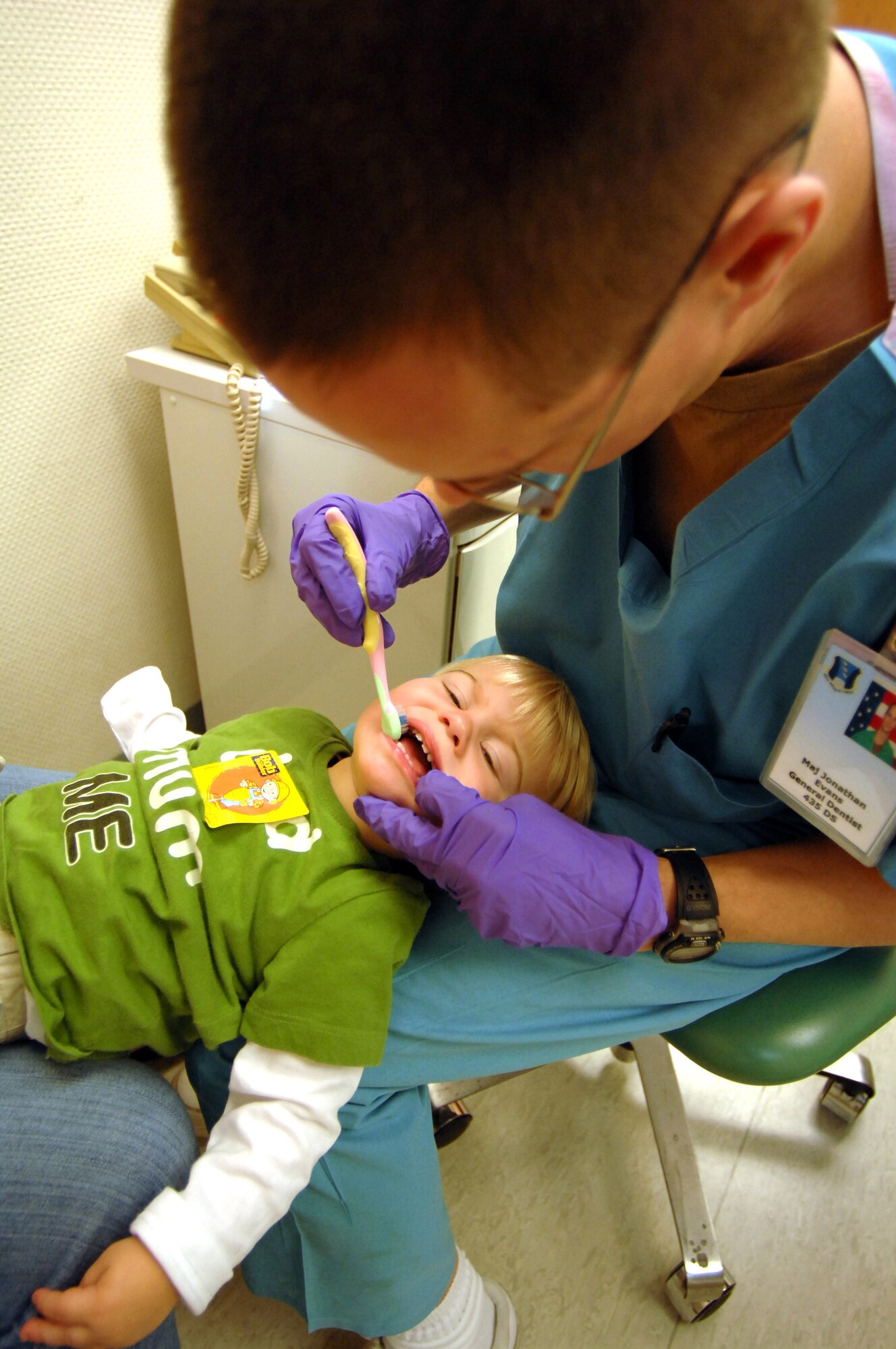 U.S. Air Force Maj. (Dr,) Jonathan Evan, 86th Medical Group general dentist, flosses Hayden Voss's teeth during his first trip to the dentist. Dentists at the 86th Dental Squadron see hundreds of children each year from the Kaiserslautern Military Community. For the initial visit, Doctor Evans emphasizes the importance of parental involvement and the child's overall dental well-being. (U.S. Air Force photo by Tech. Sgt. Michael Voss) 