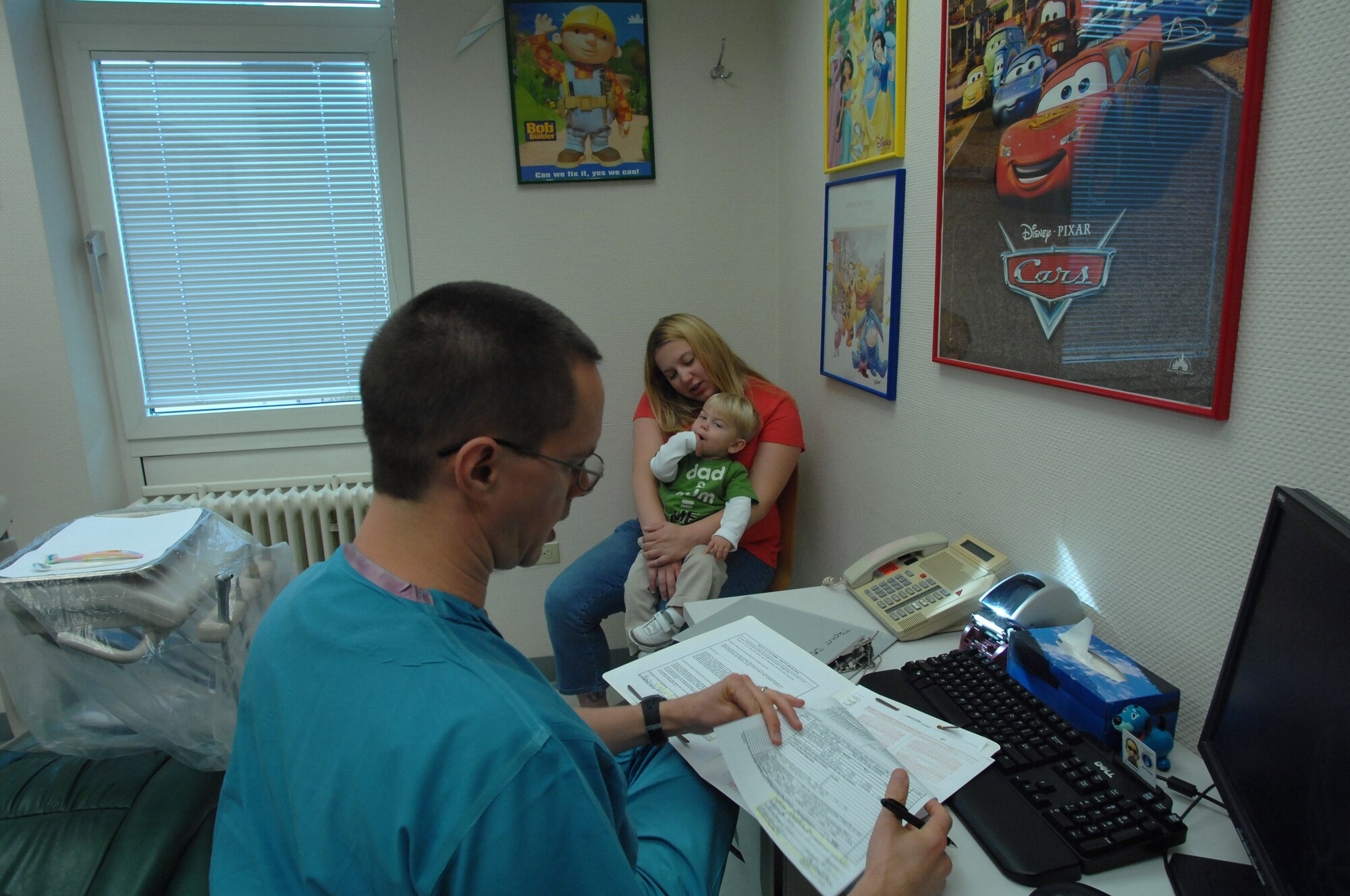 U.S. Air Force Maj. (Dr,) Jonathan Evan, 86th Medical Group general dentist, reads over Hayden Voss's records during his first trip to the dentist. Dentists at the 86th Dental Squadron see hundreds of children each year from the Kaiserslautern Military Community. For the initial visit, Doctor Evans emphasizes the importance of parental involvement and the child's overall dental well-being. (U.S. Air Force photo by Tech. Sgt. Michael Voss) 