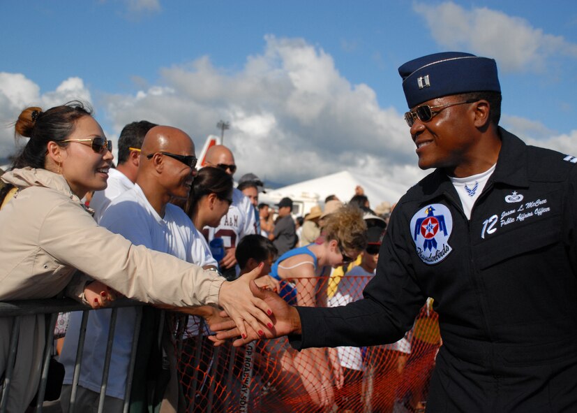 HICKAM AIR FORCE BASE, Hawaii -- Capt. Jason McCree, Thunderbird #12 Public Affairs Officer, slaps hands down the line of fans seeking autographs after their final performance Sept. 20 at Hickam?s 2009 ?Wings Over the Pacific? Open House. The Thunderbirds demonstrate the capabilities the F-16 Fighting Falcon by performing combat maneuvers during their aerial demonstration. This is Hickam's first open house since 2003, and a crowd of nearly 100,000 paid a visit during the weekend. (U.S. Air Force photo/Staff Sgt. Mike Meares)