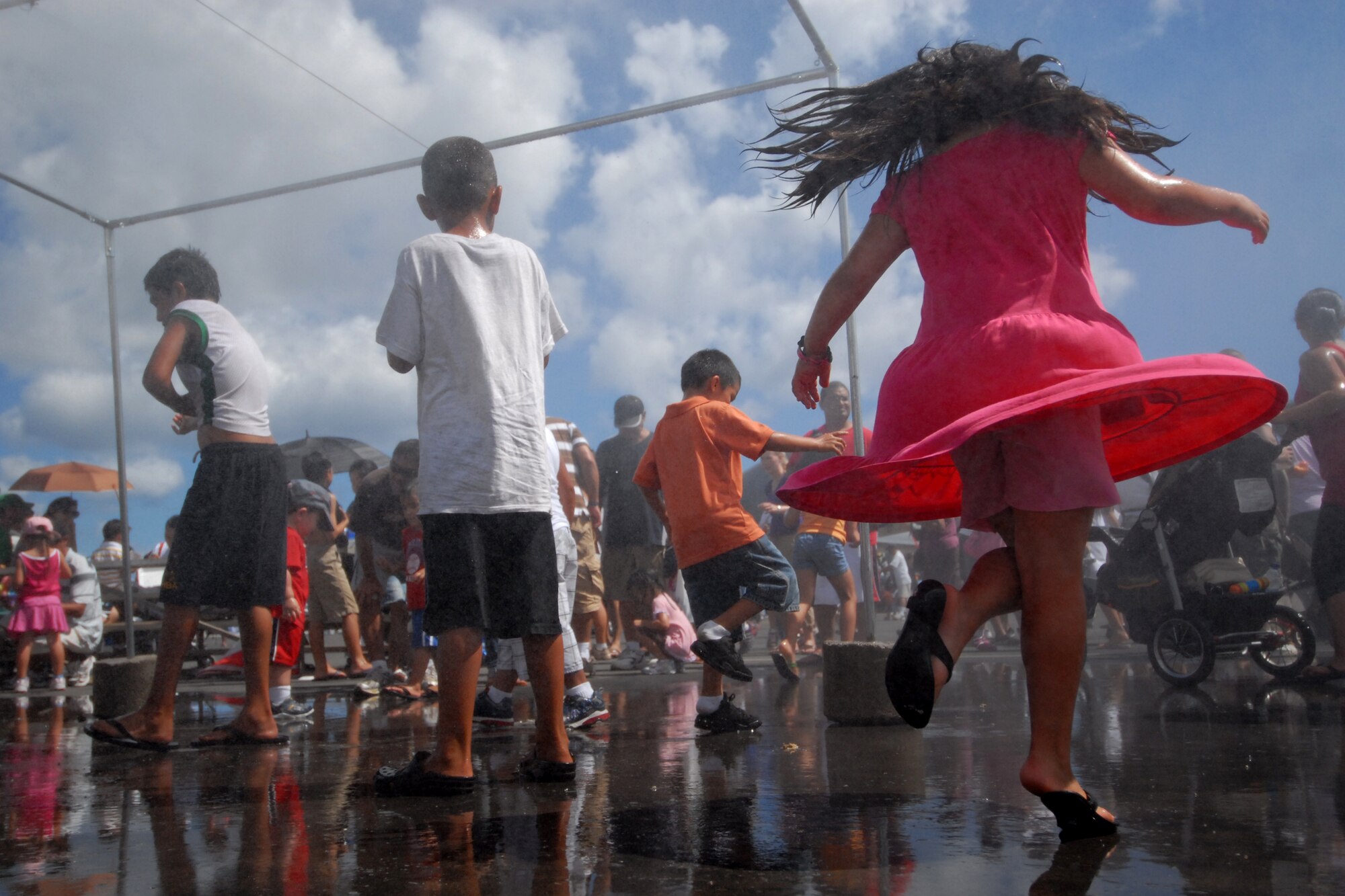 HICKAM AIR FORCE BASE, Hawaii -- Children play in the spray of water at Hickam?s 2009 ?Wings Over the Pacific? Open House Sept.20.  The Thunderbirds, U.S. Air Force Demonstration Squadron, were the headliners during the Sept. 19 and 20 event. They performed before a crowd of more than 57,000 on Sunday. The Thunderbirds demonstrate the capabilities the F-16 Fighting Falcon by performing combat maneuvers during their aerial demonstration. This is Hickam's first open house since 2003, and a crowd of nearly 100,000 paid a visit during the weekend. (U.S. Air Force photo/Staff Sgt. Mike Meares)