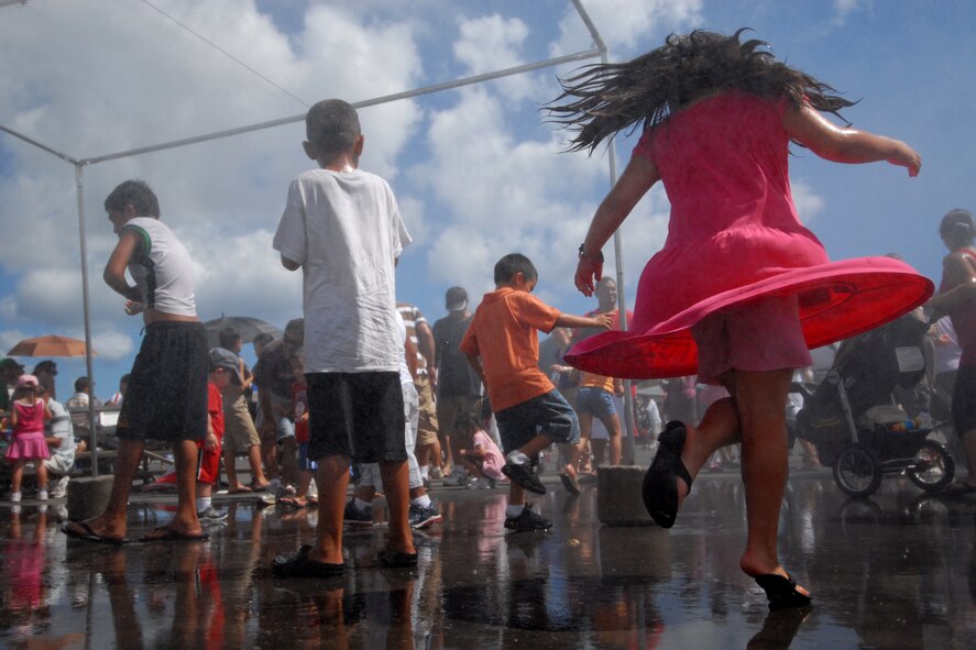 HICKAM AIR FORCE BASE, Hawaii -- Children play in the spray of water at Hickam?s 2009 ?Wings Over the Pacific? Open House Sept.20.  The Thunderbirds, U.S. Air Force Demonstration Squadron, were the headliners during the Sept. 19 and 20 event. They performed before a crowd of more than 57,000 on Sunday. The Thunderbirds demonstrate the capabilities the F-16 Fighting Falcon by performing combat maneuvers during their aerial demonstration. This is Hickam's first open house since 2003, and a crowd of nearly 100,000 paid a visit during the weekend. (U.S. Air Force photo/Staff Sgt. Mike Meares)