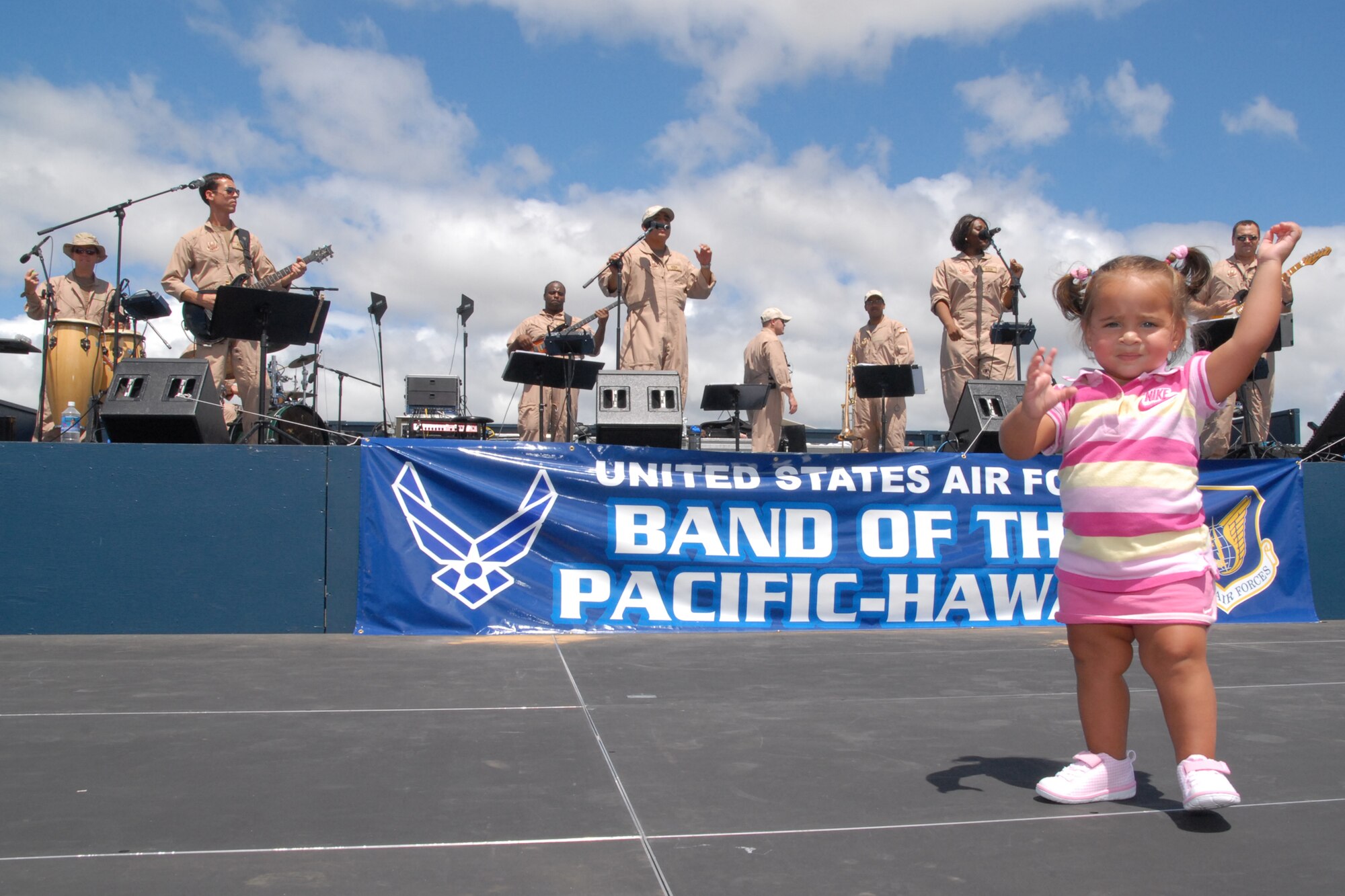 HICKAM AIR FORCE BASE, Hawaii -- Jasmine Hornbuckle dances to the tunes of the Pacific Air Force Band during the Open House ?Wings Over the Pacific? weekend. The Thunderbirds, U.S. Air Force Demonstration Squadron, were the headliners during the open house. They demonstrate the capabilities the F-16 Fighting Falcon by performing combat maneuvers during their aerial demonstration. This is Hickam's first open house since 2003, and a crowd of nearly 100,000 paid a visit during the weekend. Jasmine?s father, Tech. Sgt. Michael Hornbuckle, a trombone player, is a member of the band. (U.S. Air Force photo/Staff Sgt. Mike Meares)