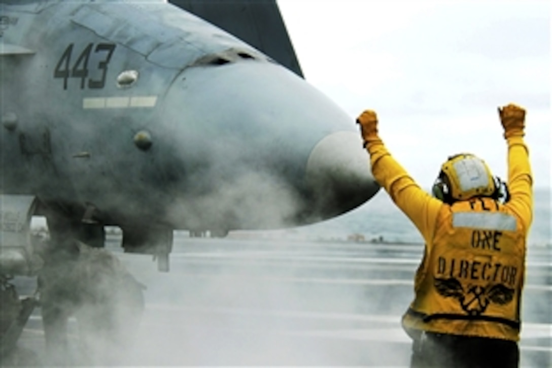 U.S. Navy Petty Officer 2nd Class Raul Barrios guides an F/A-18C Hornet aircraft from Strike Fighter Squadron 125 onto catapult one aboard the aircraft carrier USS John C. Stennis in the Pacific Ocean, Sept. 19, 2009. The Stennis is under way conducting fleet replacement squadron carrier qualifications off the coast of Southern California. 