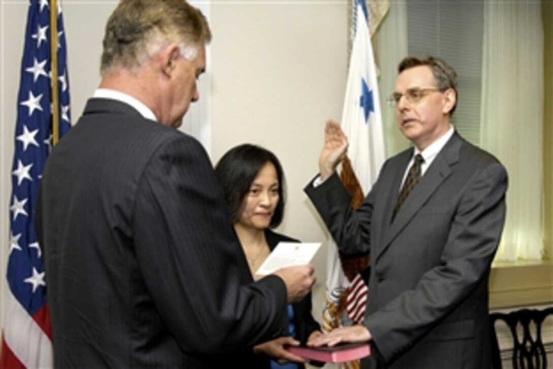 Deputy Defense Secretary William J. Lynn III, left, administers the oath of office to Dr. J. Michael Gilmore, the newly appointed director of Operational Test and Evaluation at the Pentagon, Sept. 23, 2009. Gilmore's wife, Ai Chi Liu, holds the Bible.