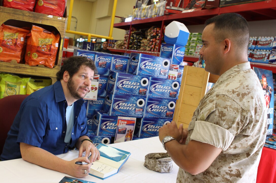 Comedian Jeffrey Ross signs a copy of his new book, “I Only Roast The Ones I Love,” for Sgt. Tim J. Orendain, motor transport mechanic, Combat Logistics Battalion 1, Combat Logistics Regiment 1, 1st Marine Logistics Group. Ross sat at Mainside’s Country Store talking to service members and families from 4 to 6 p.m., Sept. 23.