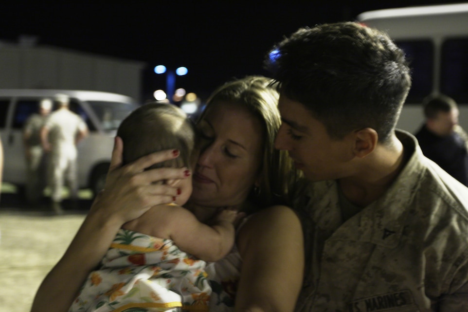 Lance Cpl. Michael Dominguez, a grenadier for Company B, 3rd Light Armored Reconnaissance Battalion, holds his wife, Kimberley, and 6-momth-old baby girl, Averie, at the 3rd LAR homecoming Sept. 24 at the Comabt Center's Victory Field.