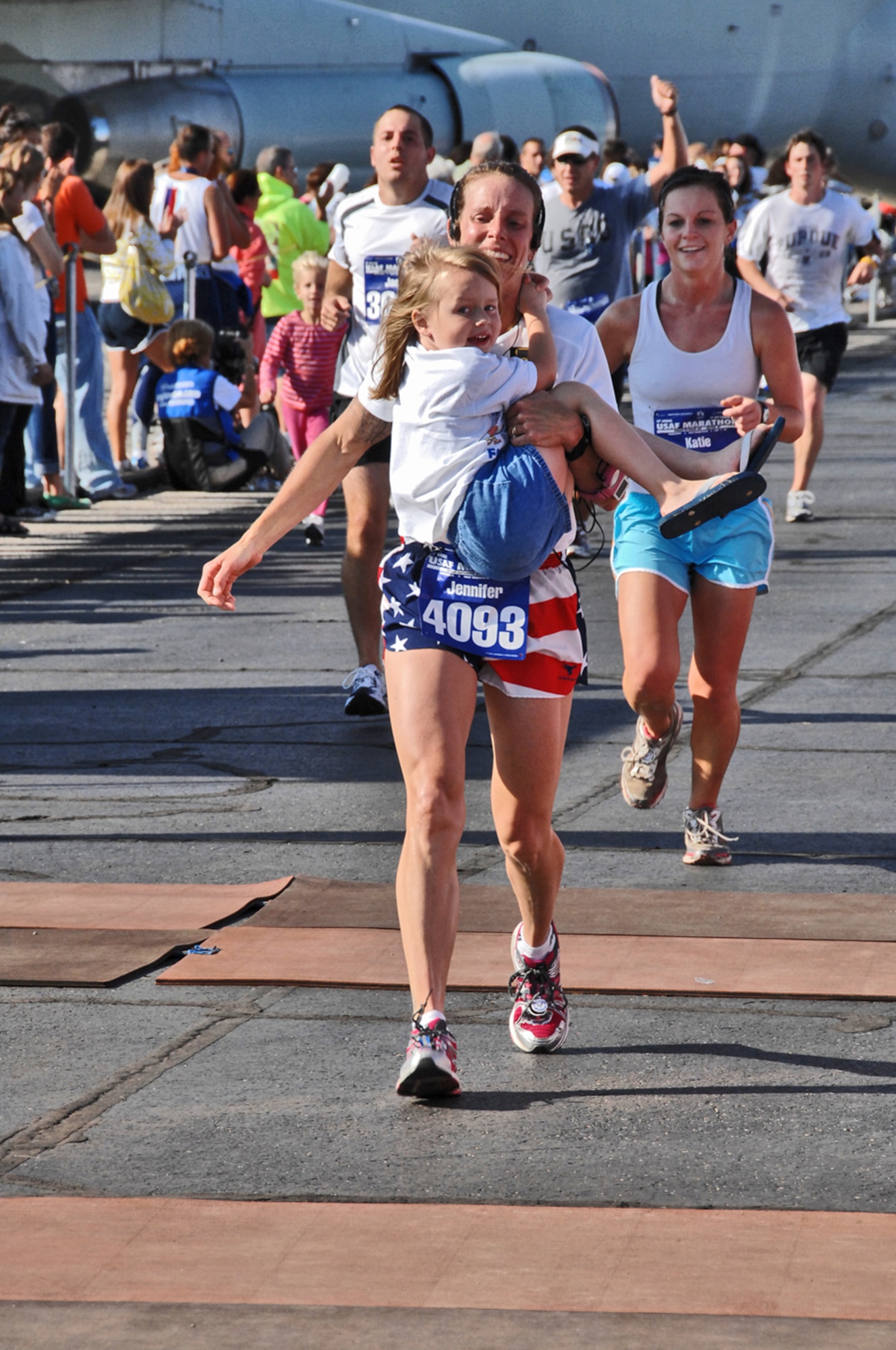 Jennifer Godsey crosses the finish line for the half marathon with her daughter Taylor clinging to become a part of the U.S. Air Force Marathon Sept. 19, 2009 at Wright-Patterson Air Force Base, Ohio. A record of nearly 10,000 runners participated. Ms. Godsey is a police officer with the City of Dayton.  (Air Force photo/Ben Strasser)
