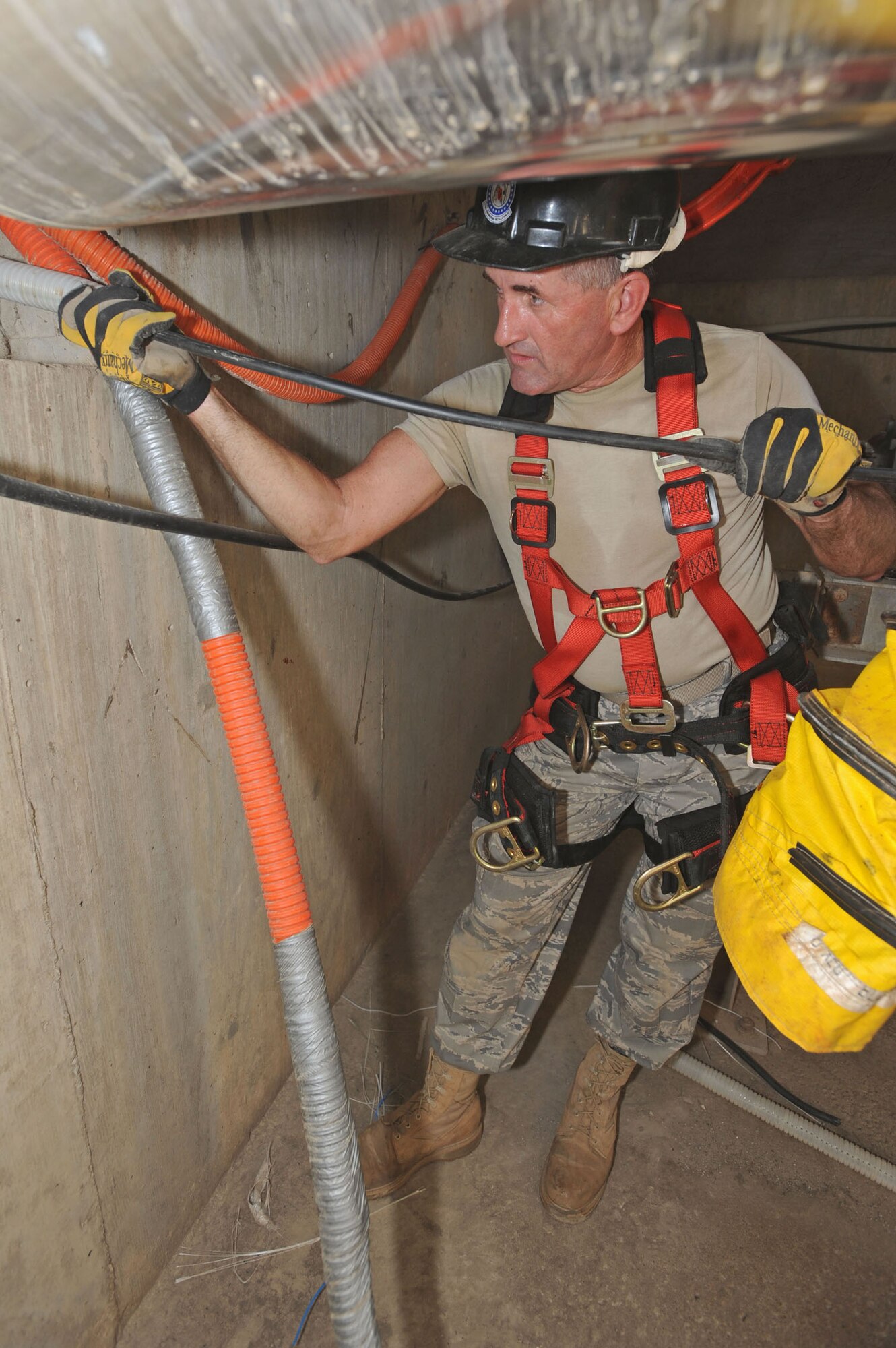 WHITEMAN AIR FORCE BASE, Mo. - Staff Sgt. Darreyl Walker, 217th Engineering Installation Squadron cable systems technician, guides fiber optic cable through plastic piping, Sept. 24. Sergeant Walker is running 300 feet of cabling and then will splice the ends together to make one complete cable. (U.S. Air Force photo/Airman 1st Class Carlin Leslie)