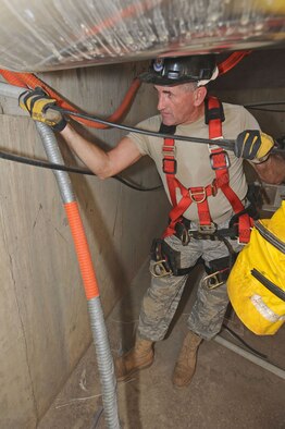 WHITEMAN AIR FORCE BASE, Mo. - Staff Sgt. Darreyl Walker, 217th Engineering Installation Squadron cable systems technician, guides fiber optic cable through plastic piping, Sept. 24. Sergeant Walker is running 300 feet of cabling and then will splice the ends together to make one complete cable. (U.S. Air Force photo/Airman 1st Class Carlin Leslie)