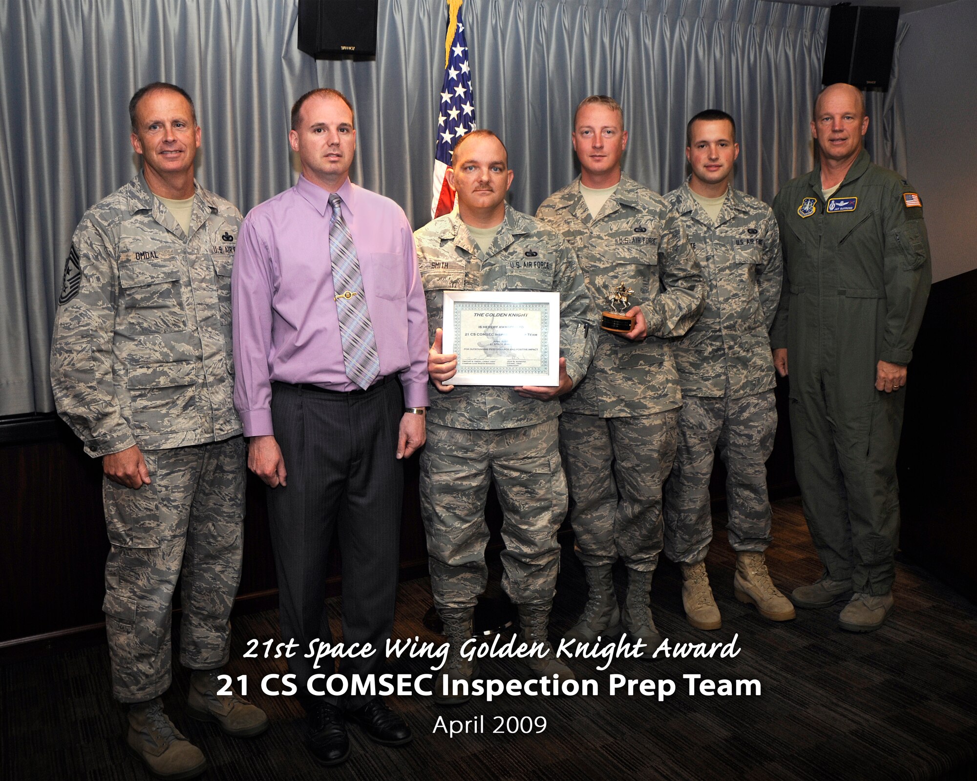Col. Jay Raymond, 21st Space Wing commander (right) and Chief Master Sgt. Tim Omdal, 21st SW chief master sergeant (left), presented the 21st Space Wing Golden Knight Award for April to the 21st Communications Squadron COMSEC Inspection Prep Team. The team was nominated for its hard work getting the entire base’s COMSEC program up to the appropriate level, including training sessions and education efforts base-wide. (Air Force photo by Craig Denton)