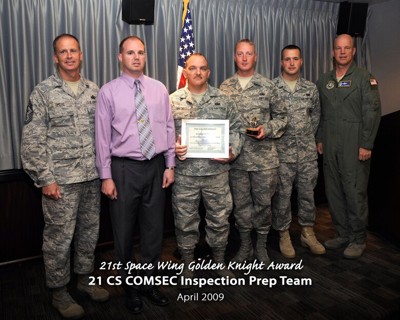 Col. Jay Raymond, 21st Space Wing commander (right) and Chief Master Sgt. Tim Omdal, 21st SW chief master sergeant (left), presented the 21st Space Wing Golden Knight Award for April to the 21st Communications Squadron COMSEC Inspection Prep Team. The team was nominated for its hard work getting the entire base’s COMSEC program up to the appropriate level, including training sessions and education efforts base-wide. (Air Force photo by Craig Denton)