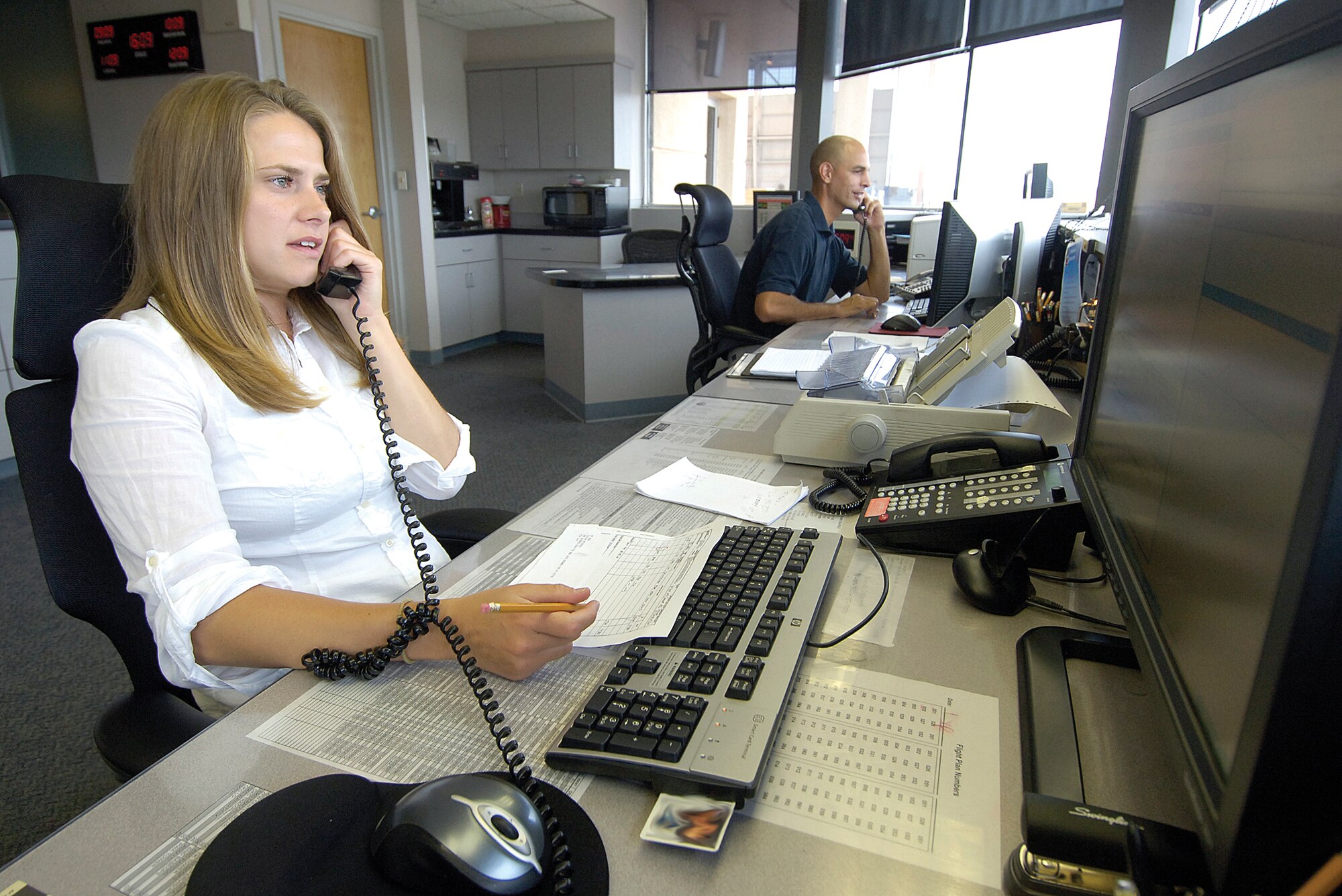 Michelle Houston, airfield management operations coordinator, approves aircraft movement into and out Tinker. She is checking flight plans, approving aircraft and coordinating with aircrews and air traffic control. (Air Force photo by Margo Wright)