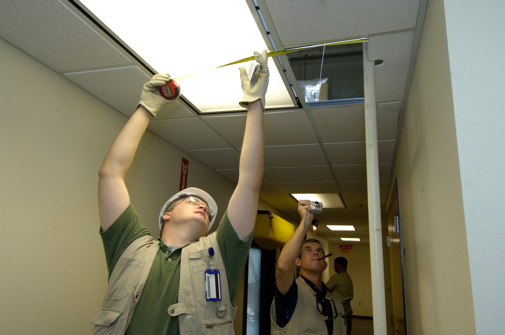 Chad Williams, left, and Harold Keck perform a building inspection. The two were part of an 11-person facility inspection team, from the 72nd Maintenance Engineering Office,  combs over a Tinker Building. They are inventorying and cataloguing anything and everything about the building. The look at everything from water fountains to roof access, documenting everything that needs repair now or in the future. The team inspects more than 3 million square feet per year. (Air Force photo by Margo Wright)