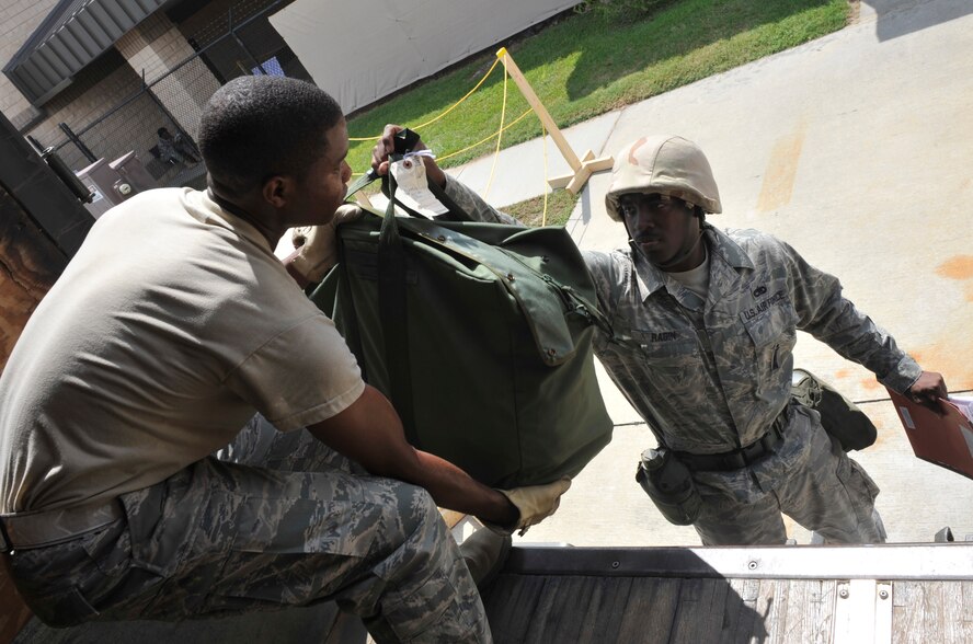 MOODY AIR FORCE BASE, Ga. -- Airman First Class Lamaro Colvin, 23rd Logistics Readiness Squadron vehicle management and analysis member, takes a mobility bag from Staff Sgt. Harrison Ragin, 23rd Aircraft Maintenance Squadron aircraft armament technician, during the Phase I Operational Readiness Inspection here Sept. 21. (U.S. Air Force photo by Senior Airman Schelli Jones)