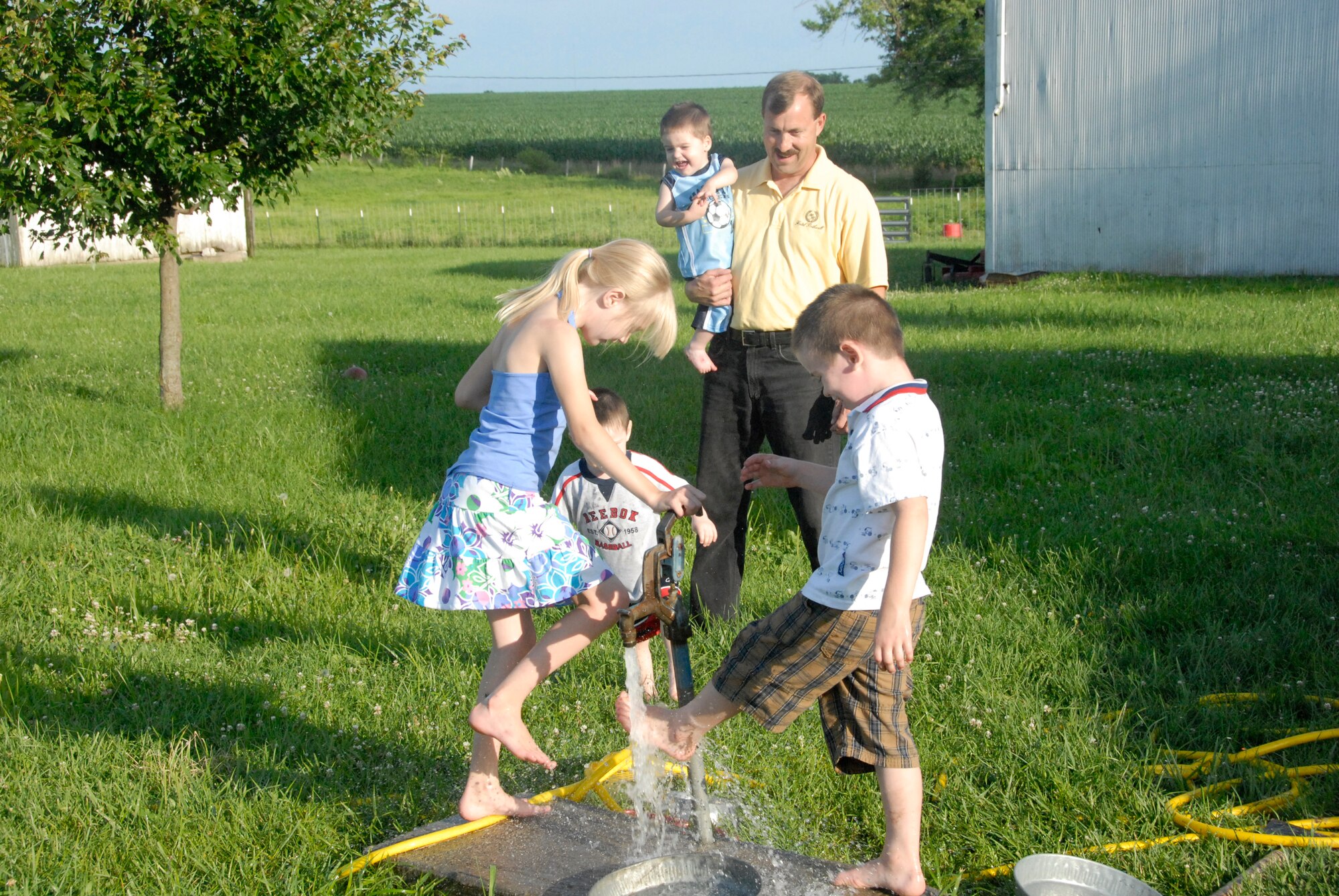 Tech. Sgt. Eric Anderson, 442nd Aircraft Maintenance Squadron, holds one of his foster children as he watches his daughter and his other foster sons enjoy playing in a water hydrant on a warm afternoon in their yard.  Sergeant Anderson, an A-10 crew chief, and his wife have been foster parents for several children in the past few years.  Sergeant Anderson is an Air Force Reservist in the 442nd Fighter Wing, which is based at Whiteman Air Force Base, Mo.  (U.S. Air Force photo/Senior Airman Danielle Wolf)