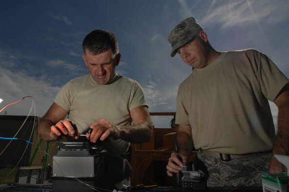 WHITEMAN AIR FORCE BASE, Mo. - U.S. Air National Guardsmen Staff Sgt. Darry Walker (left), 217th Engineering Installation Squadron, Springfield, Ill., and Tech Sgt. Gary Farmer, 241st Engineering Installation Squadron, Chattanooga, Tenn., work together to fuse a strand of fiber optic cable, Sept. 24. Air National Guard members from both the 271st and the 241st spent more than two months at Whiteman replacing copper transmission cable with more efficient fiber optic cable. The fiber optic cable will provide 50 percent more capability and expansion to utilize a greater number of networked products. (U.S. Air Force photo/Senior Airman Kenny Holston)