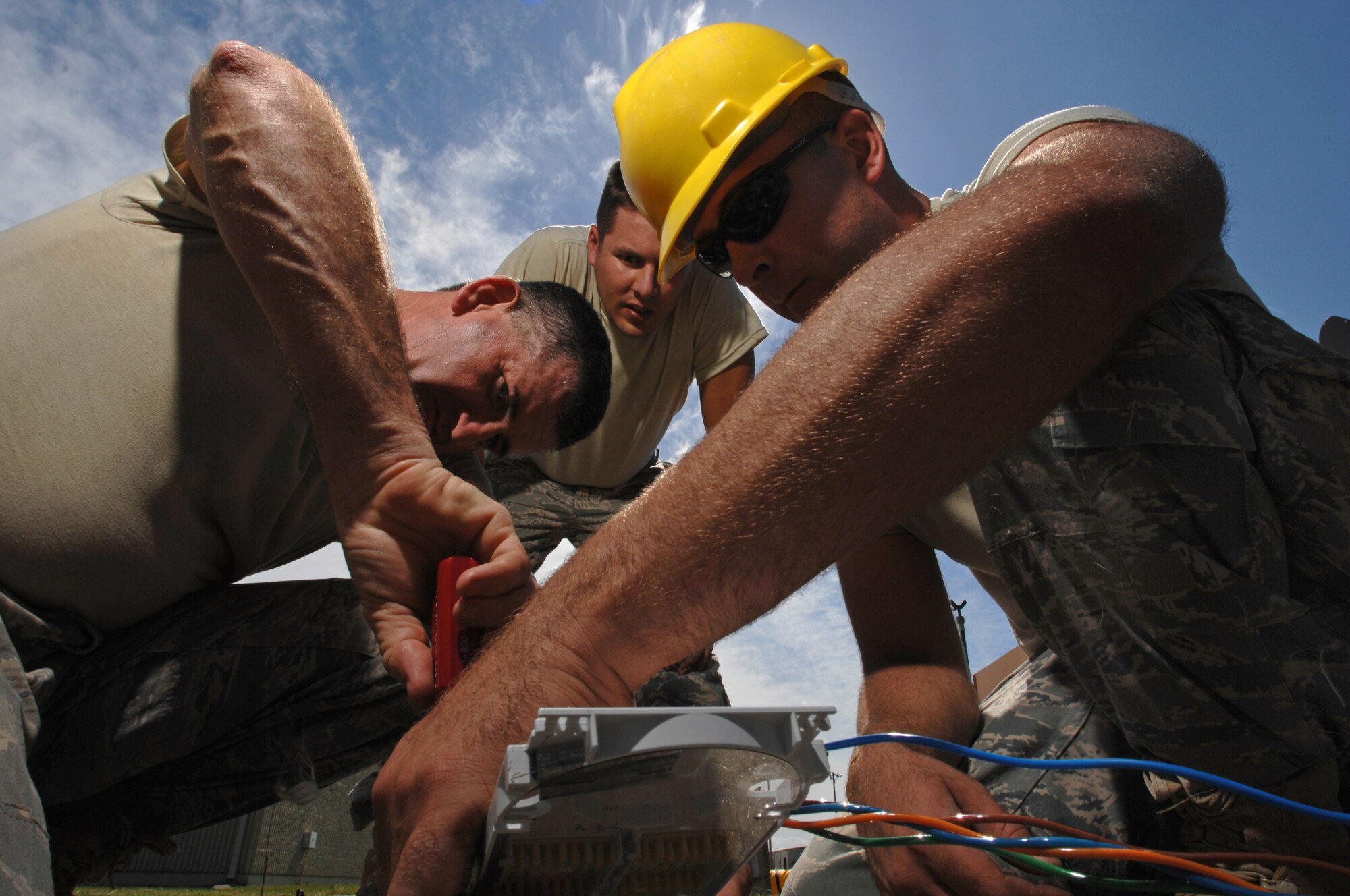WHITEMAN AIR FORCE BASE, Mo. - U.S. Air National Guardsmen, Staff Sgt. Darry Walker (left), Staff Sgt. Dustin Sims, and Master Sgt. Mike Leddy, all 217th Engineering Installation Squadron, Springfield, Ill., work together to loosen a fiber optic cable housing to gain better access to the cable prior to separating the several colored stands of fiber optic cable Sept. 24. Air National Guard members from both the 271st and the 241st have spent more than two months at Whiteman AFB replacing copper transmission cable with more efficient fiber optic cable. The fiber optic cable will provide 50 percent more capability and expansion to utilize a greater number of networked products. (U.S. Air Force photo/ Senior Airman Kenny Holston)