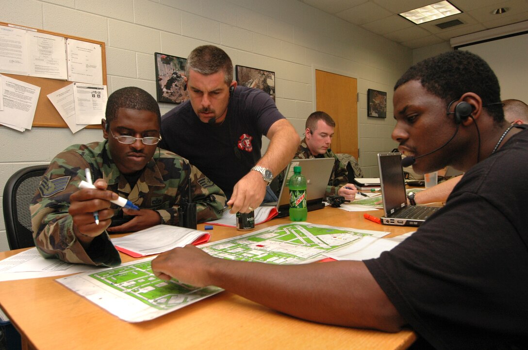 Staff Sgt. Brandon Riggins, left, 4th Civil Engineer Squadron firefighter, Seymour Johnson Air Force Base, N.C., Lt. Donald Simms, center, and Staff Sgt. Terrence Bowman, both Andrews fire fighters, plot out the location of a fire on a map of a make-believe fire scenario, while following audio instructions during a table top exercise  during the exercise inside a conference room at Fire Station II on the east side of base Tuesday.  The session was part of a 12-day skill and leadership level training provided by two instructors from the Department of Defense Fire Academy, Goodfellow Air Force Base, Texas. A total of 10 military and civilian firefighters from Andrews, Seymour AFB and Fort Myer will receive Fire Officer II certification and Incident Safety Officer certification upon completion of the course. (U.S. Air Force photo/ Bobby Jones)
