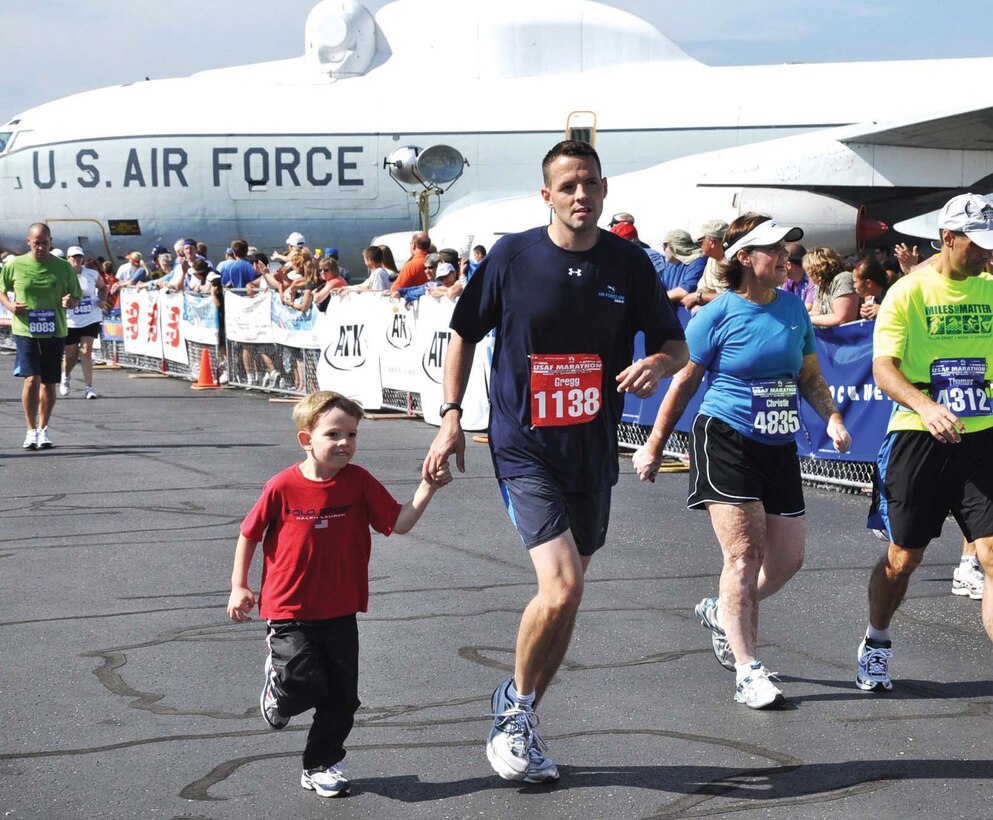 Gregg Jerome, Presidential Logistics Squadron, crosses the finish line accompanied by his son John Sept. 19 at the Air Force Marathon at Wright-Patterson AFB, Ohio. Twelve runners from the Presidential Airlift Group ran the marathon, and every one of them finished. (Courtesy Photo)