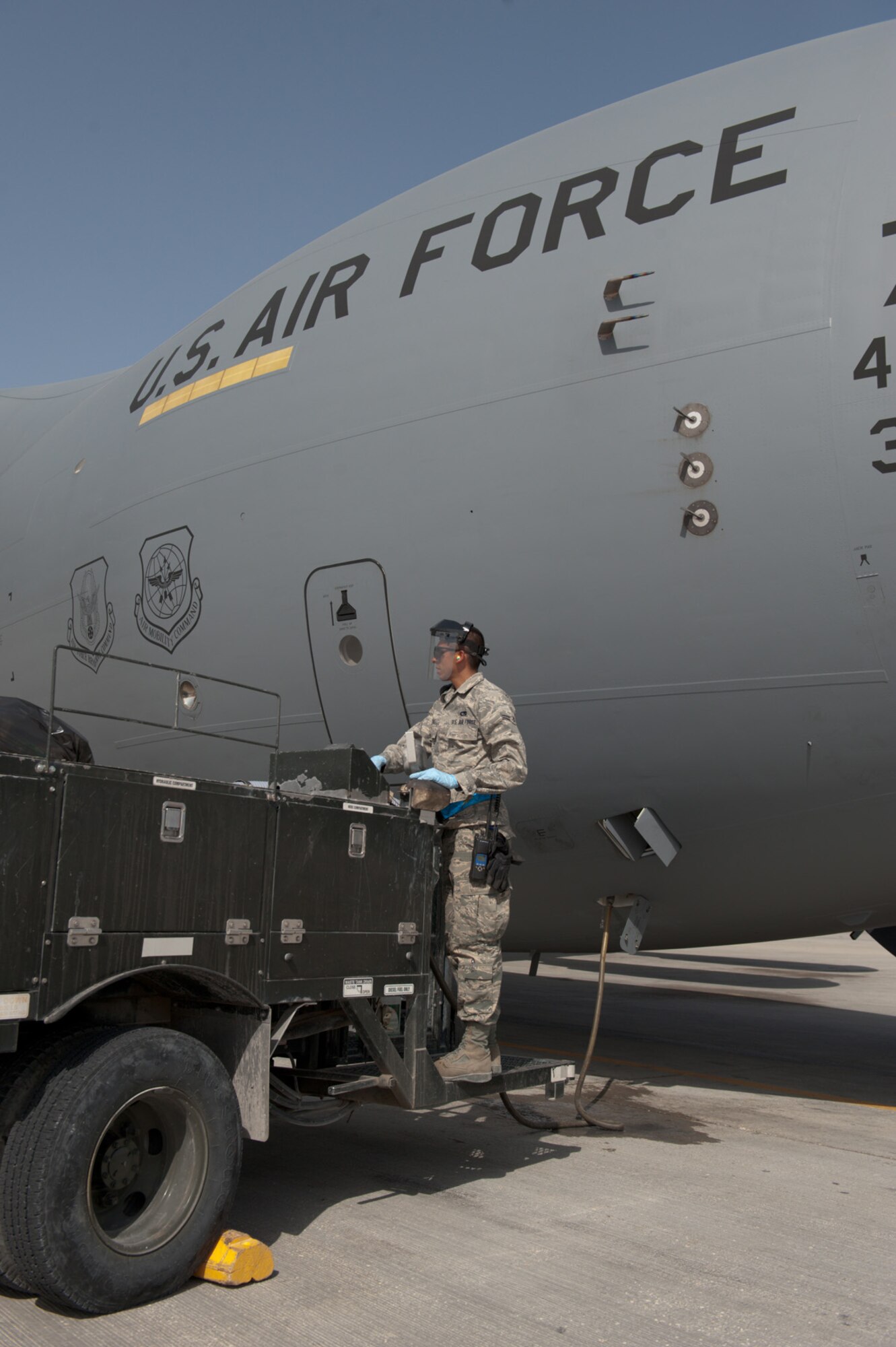 Airman 1st Class Julio Pernas, 8th Expeditionary Air Mobility Squadron fleet service representative, performs service on a C-17 Globemaster III, Sept. 24, in Southwest Asia. Airman Pernas, along with other members of 8 EAMS ramp section, provide fleet services for all aircraft. Airman Pernas is deployed from Ramstein Air Base, Germany in support of Operations Iraqi and Enduring Freedom. (U.S. Air Force photo/Staff Sgt. Robert Barney) 