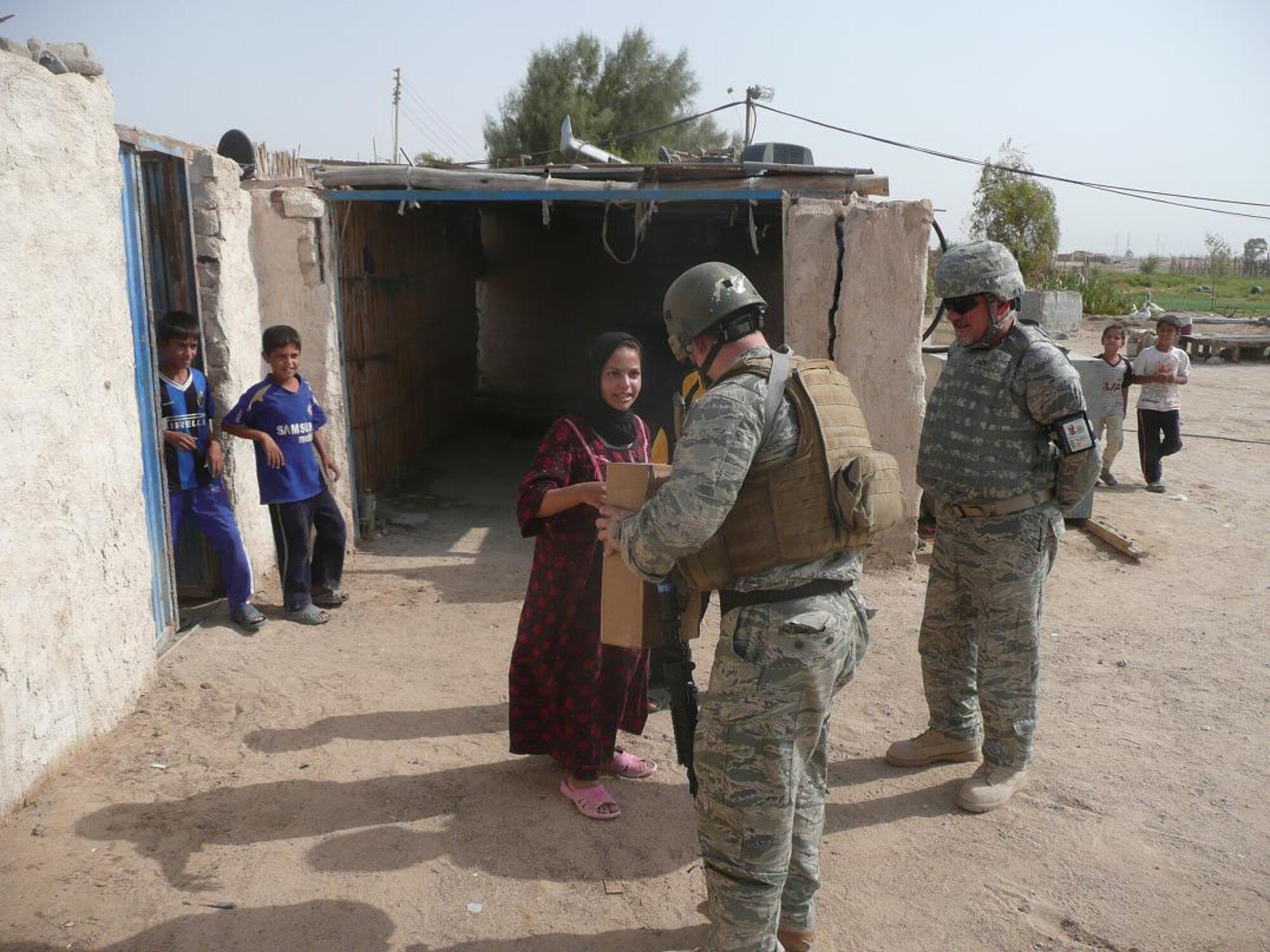 Tech. Sgt. Ben Martin, 887th Expeditionary Security Forces Squadron, hands a thank-you gift to a young Iraqi girl Sept. 18, 2009, as an 887th ESFS translator looks on. The girl found and reported an explosively formed penetrator, or EFP, outside of Camp Bucca, Iraq, in an area that 887th ESFS Airmen regularly patrol. (U.S. Air Force photo)