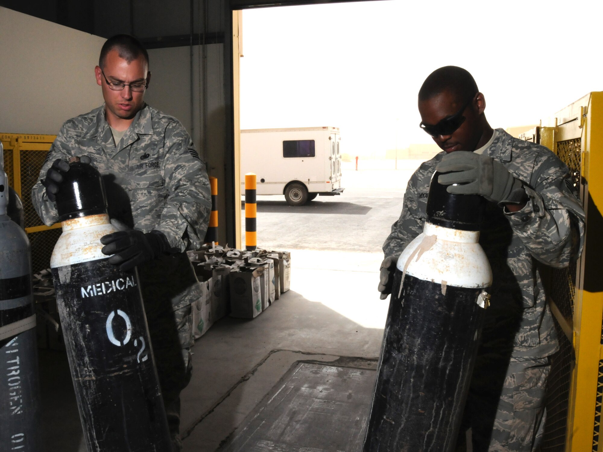 Staff Sgt. Anthony Laugen, 379th Expeditionary Logistics Readiness Squadron hazardous materiel NCO in-charge, and Senior Airman Jeremy Hoover, 379 ELRS HAZMAT technician, refill empty oxygen tanks here, Sept. 23. Senior Airman Jeremy Hoover, 379th Expeditionary Logistics Readiness Squadron hazardous materiel technician, refills empty oxygen tanks, here, Sept. 23. The 379 ELRS storage and issue facility maintains a $400k contract consisting of more than 20 different cylinder gases utilized at this undisclosed location in Southwest Asia. Sergeant Laugen is deployed from Spangdahlem Air Base, Germany; Airman Hoover is deployed from McConnell Air Force Base, Kan. Both are deployed in support of Operations Iraqi and Enduring Freedom. (U.S. Air Force Photo/Tech. Sgt. Jason W. Edwards)