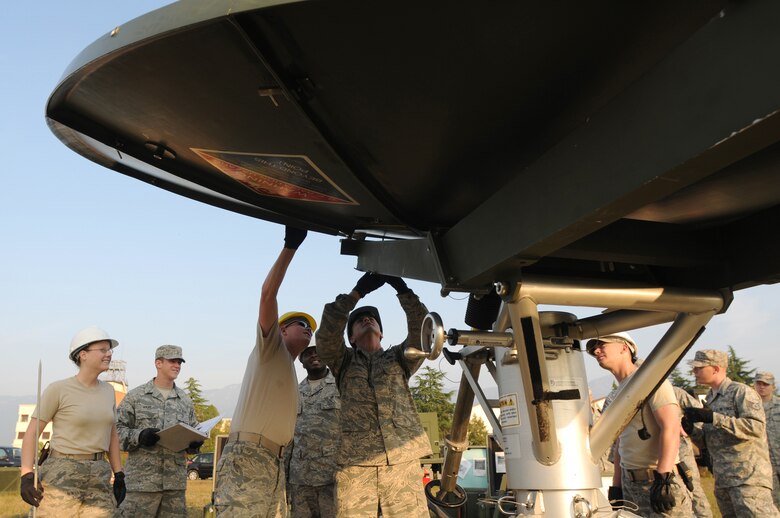 Staff Sgt. Nathan Bonds (center), 1st Combat Communications Squadron radio maintenance, locks a panel on a USC-60 satellite into place Sept. 22, 2009 at Aviano Air Base, Italy, during a weeklong training exercise.  Fellow radio and satellite communications Airmen gather around as the two career fields undergocross-flow training in preparation for their upcoming merger to transmission systems in October 2009. (U.S. Air Force photo/Staff Sgt. Patrick Dixon)