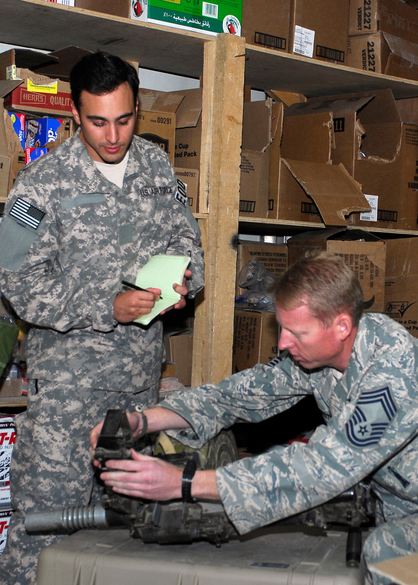 BAGRAM AIRFIELD, Afghanistan -- Tech. Sgt. Richard Gibbons (left) and Chief Master Sgt. Jerry S. Shelton Jr. (right) review serial numbers on a piece of old Soviet
equipment.  The Colorado Air National Guard noncommissioned officer from Buckley Air Force Base, Colo. was awarded the Purple Heart Medal by Brig. Gen. Steven
Kwast, 455th Air Expeditionary Wing commander Sept. 19, 2009 for the wounds
he received from an Improvised Explosive Device.  (U.S. Air Force photo/Senior Airman Felicia Juenke)

