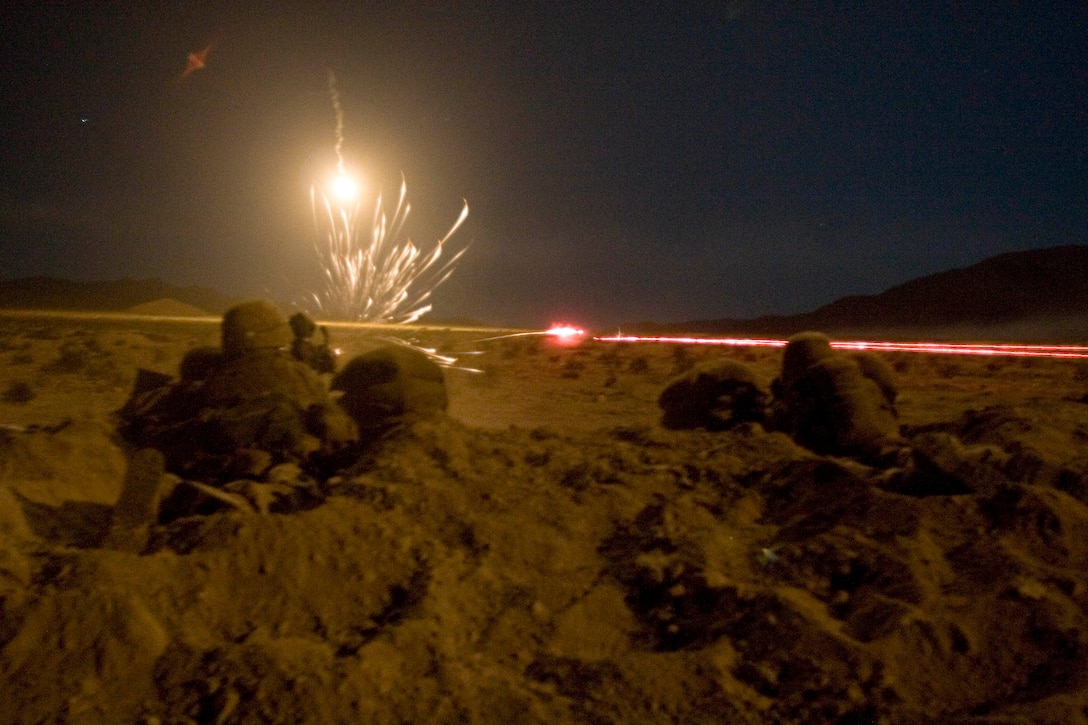 Machine guns fire red tracer rounds at enemy vehicles with an illumination flare overhead.