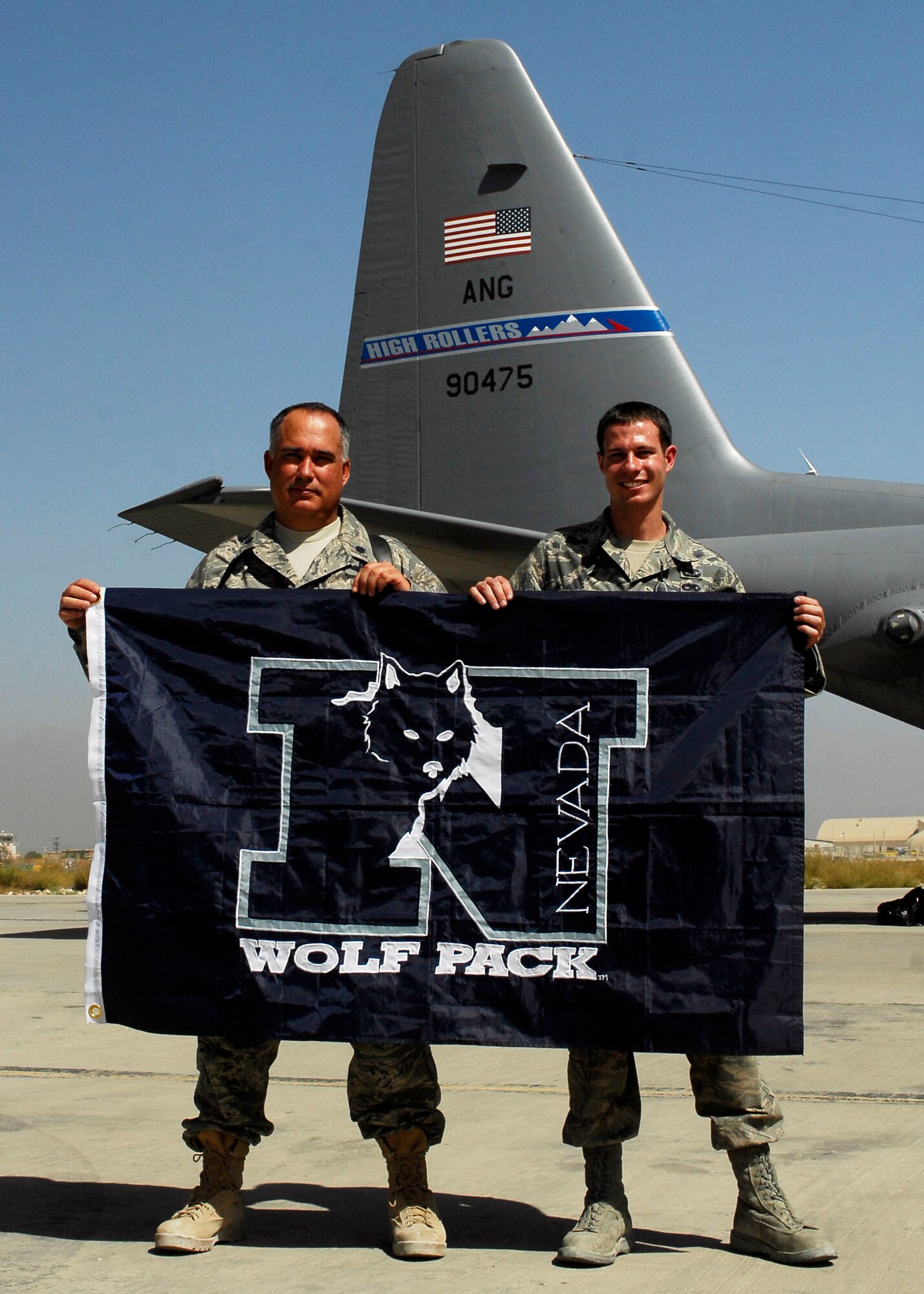 BAGRAM AIRFIELD, Afghanistan -- Lieutenant Colonel Barltey O'Toole (left) and his son Senior Airman Bartley O'Toole (right), both from the 774th Expeditionary Airlift Squadron, hold the University of Nevada flag while deployed together here Sept. 24, 2009.  Colonel O'Toole graduated from the University of Nevada and Airman O'Toole is currently a student there.  Colonel O'Toole is the Director of Operations and Airman O'Toole is an Aircrew Flight Equipment Journeyman.  "It's different, I know he's an Airman, but every time I talk to my wife she asks about him," said Colonel O'Toole "So there's that parental feeling there too."   (U.S. Air Force photo/Senior Airman Felicia Juenke)