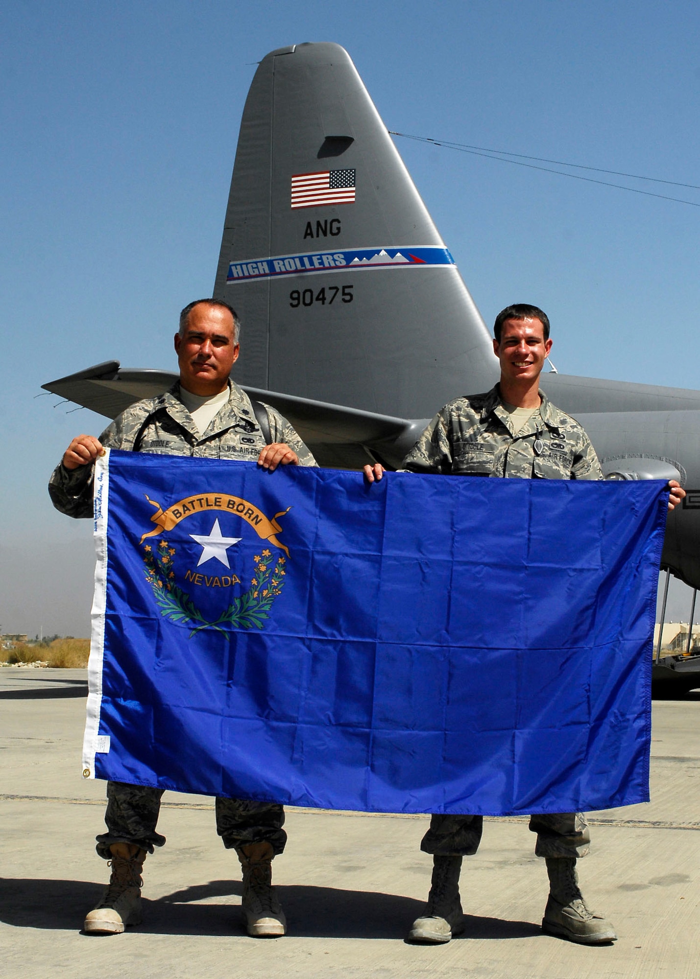 BAGRAM AIRFIELD, Afghanistan -- Lieutenant Colonel Barltey O'Toole (left) and his son Senior Airman Bartley O'Toole (right), both from the 774th Expeditionary Airlift Squadron, hold the Nevada State flag while deployed together here Sept. 24, 2009.  Colonel O'Toole is the Director of Operations and Airman O'Toole is an Aircrew Flight Equipment Journeyman.  "It feels the same as being at home station," said Airman O'Toole "We keep a professional attitude while at work and leave home at home."  (U.S. Air Force photo/Senior Airman Felicia Juenke)