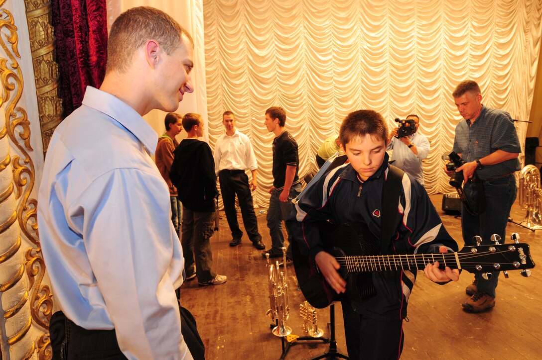 KARABALTA VILLAGE, Kyrgyzstan -- Staff Sgt. Clint Whitney, U.S. Air Forces Central Command "FALCON" band vocalist, listens to Nail Ismailov, 12, perform a song following a performance in Kyrgyzstan. The FALCON  band performed a show for the community of Karabalta while becoming very popular with audience members in attendance. The band is stationed at a base in Southwest Asia and is deployed from Offutt Air Force Base, Neb. (U.S. Air Force photo/Senior Airman Steele C. G. Britton)