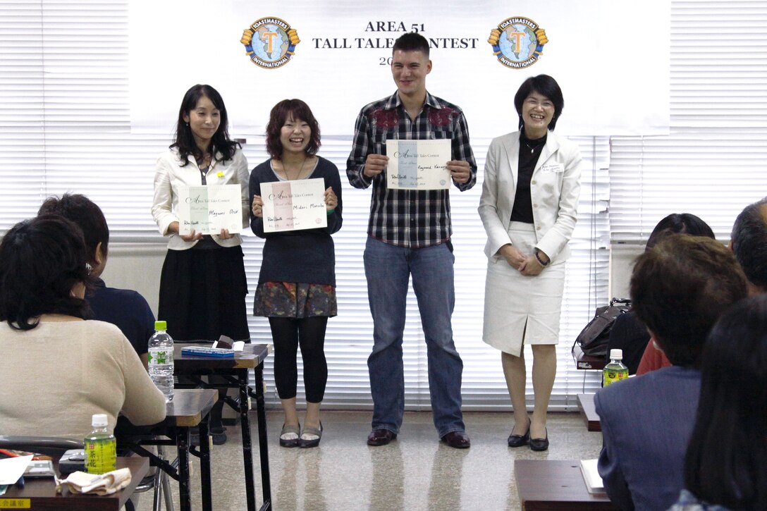 From left to right, Mayumi Ono, 3rd place contest winner, Midori Monobe, 2nd place contest winner, and Raymond Vanwey,1st place contest winner, stand next to Rika Uemoto, Area 51 Toastmasters Governor, presenting their awards to the crowd during the Area 51 Tall Tales Toastmasters contest at the Iwakuni-shi Fukushi Kaikan in Iwakuni City. The area contest was a part of a Toastmasters international contest where the 1st and 2nd place area winners will proceed to the district, division and to the international level if they continue winning. Seven contestants participated in the event where they demonstrated their public speaking capabilities. “The point of the contest was to tell tall tales, kind of like fake stories.” said Vanwey. “But all of it is to give us a better ability to speak in public. It’s difficult to get in front of a lot of people and give speeches, so making a tall tales competitions gives you a chance to use your imagination to do stuff that’s more outlandish than what you would usually do.” Vanwey won the competition by telling a tale of the biggest fish he’s ever caught, with the fish doubling in size with each reference he made to it. The next contest is scheduled Oct. 11.Toastmaster meetings aboard the station are open to ages 18 and up, with meetings taking place the second Wednesday and forth Friday of the month. Meetings take place at the facilities building in the second floor conference room from 11:45 a.m. to 12:45 p.m. and at the Marine Aviation and Logistics headquarters building in the first floor airspeed room from 7:00 to 9:00 p.m. Visitors are encouraged to come free of charge to view the proceedings or join the Toastmasters for a fee of $33.00 every six months. Anyone wanting more information on the Toastmaster can contact Michiko Yasuda,  at 253-4501.