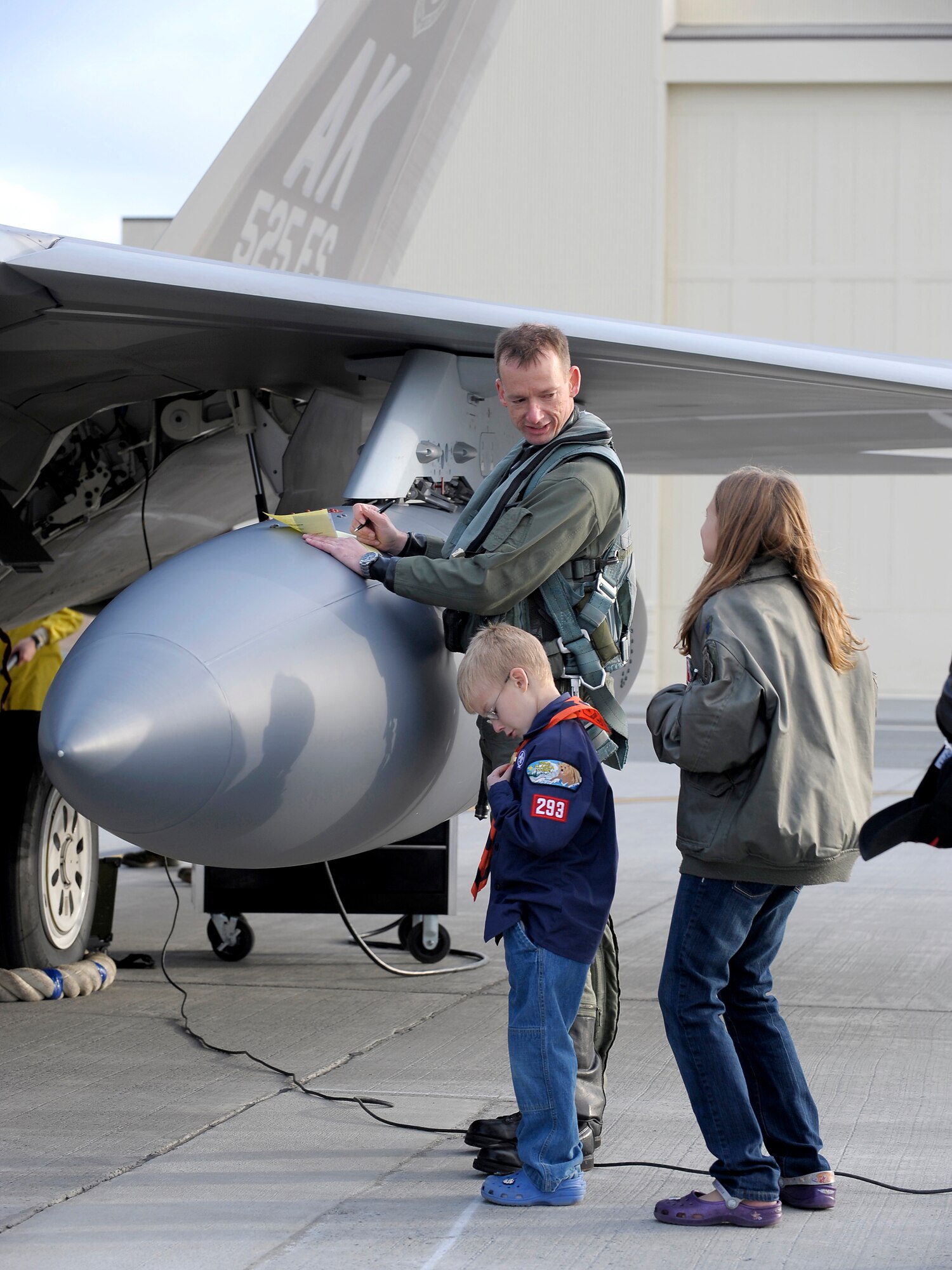 ELMENDORF AIR FORCE BASE, Alaska -- Six-year-old John Niemi, 'squares away' his Boy Scout uniform as sister, 9-year-old Lauren Niemi talks with their father, Lt. Col. Christopher Niemi as he fills out customs paperwork after arriving home from a four-month deployment to Andersen Air Force Base, Guam. Niemi is an F-22 Raptor pilot and the commander of the 525th Fighter Squadron. (U.S. Air Force photo/Master Sgt. Keith Brown)